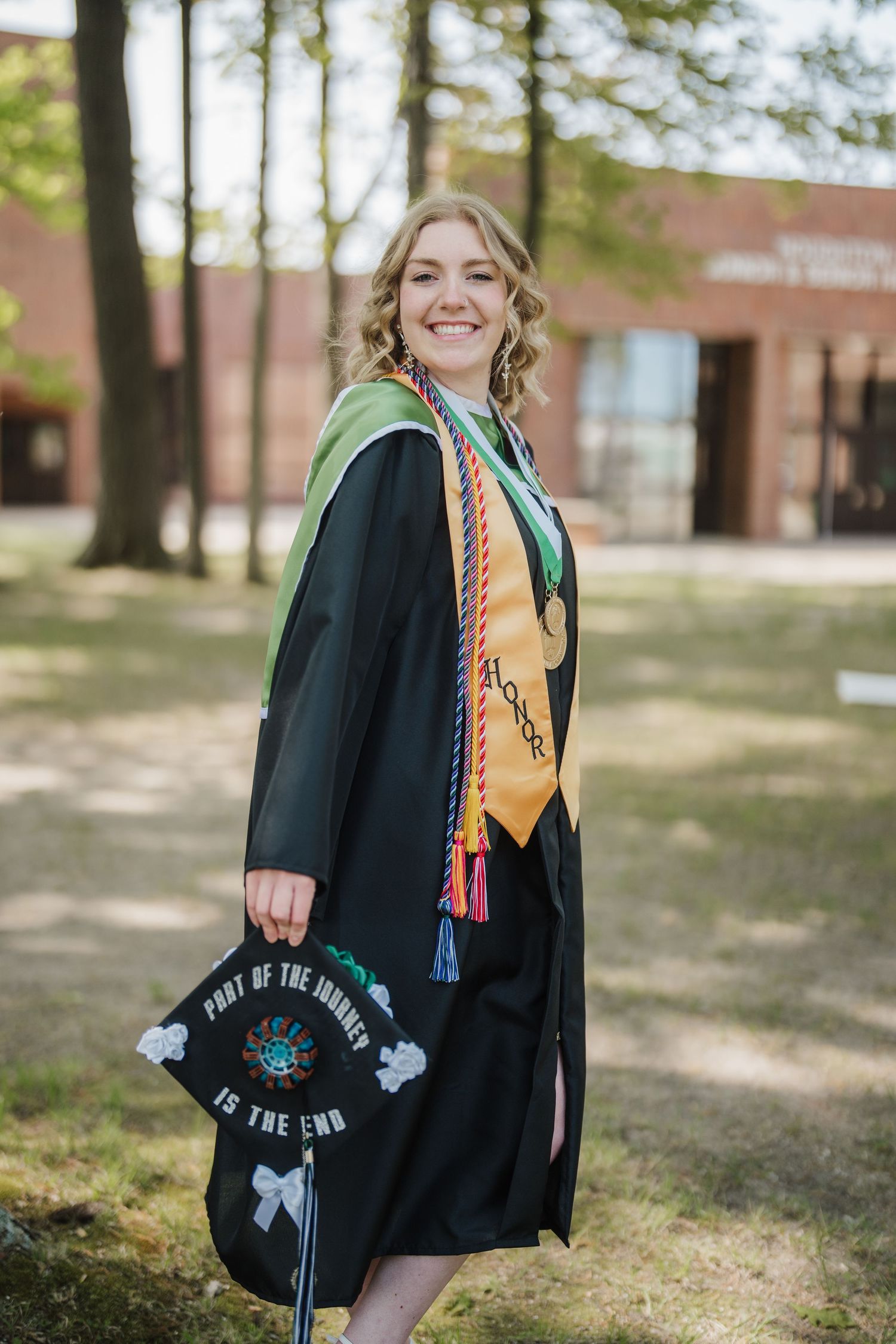 Graduation photos showing decorated cap with 'Trust the Lord' message and tassels in green and gold colors.