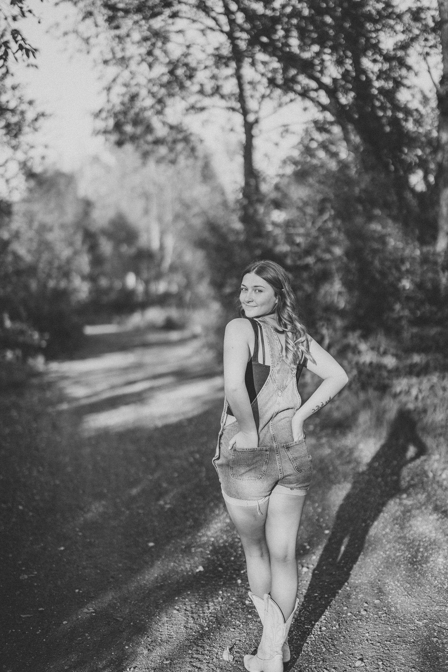 A black and white artistic portrait series captured on a winding outdoor path.