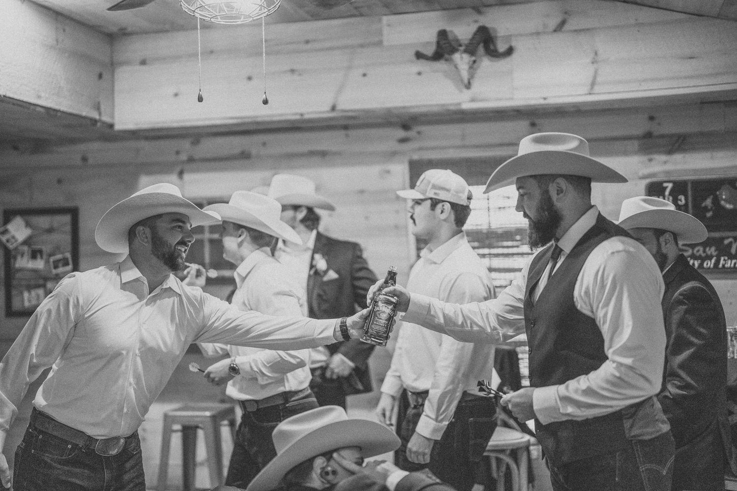 Group of men in cowboy hats and western attire enjoying a celebration in black and white.