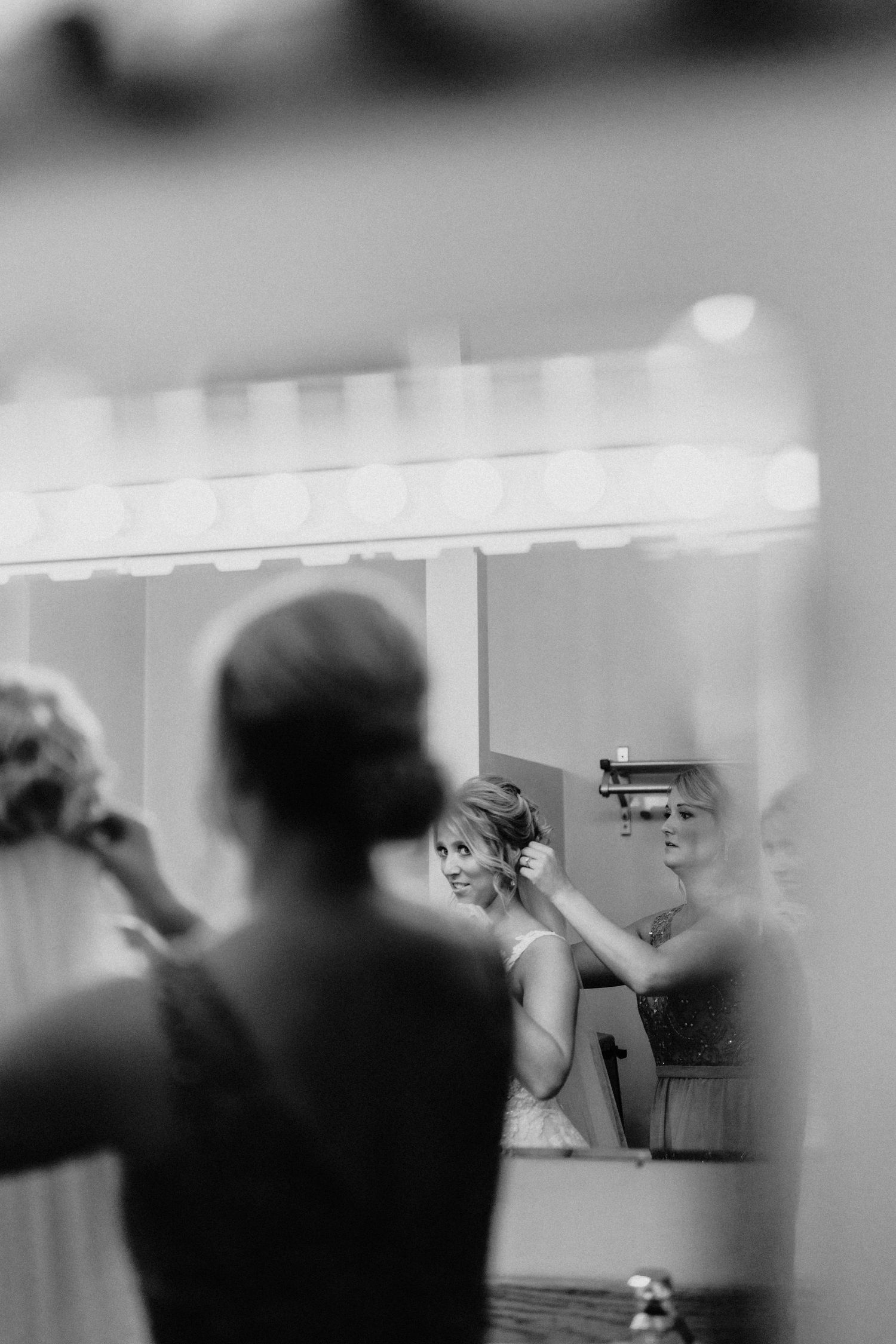 A black and white reflection of wedding preparations in a dressing room mirror.