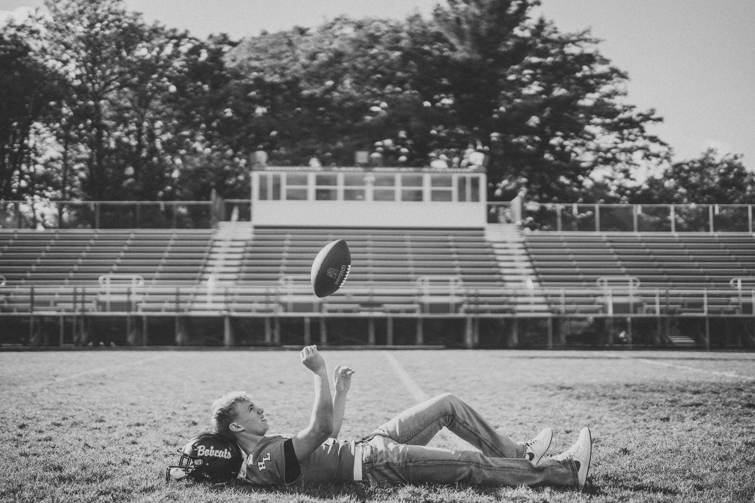A sequence of black and white photos showing a person performing a backflip on an athletic field.