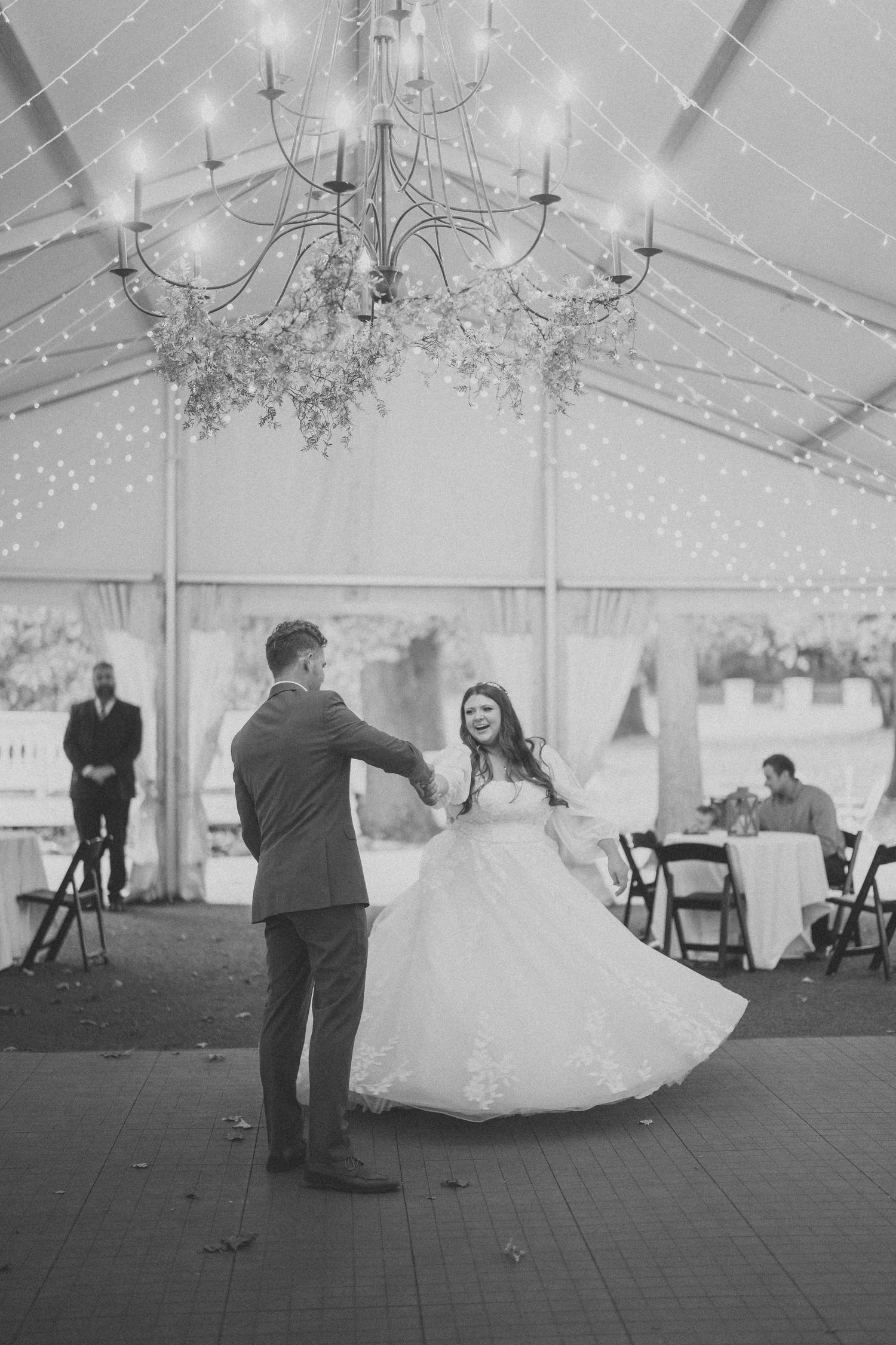 Black and white photos show a sequence of a couple dancing in a wedding tent with twinkling lights overhead.