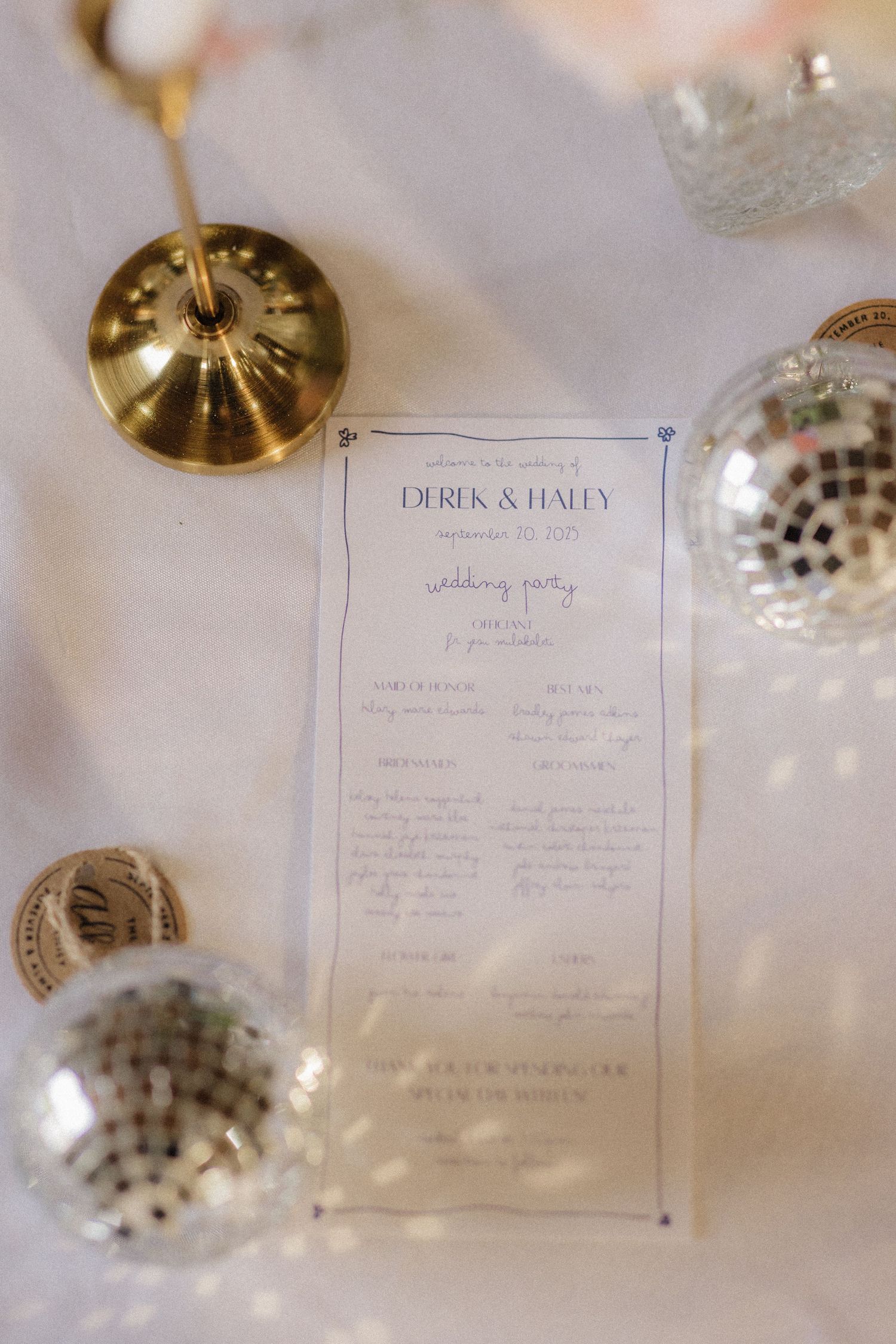 Wedding reception menu cards displayed on an elegant table setting with gold light fixtures.