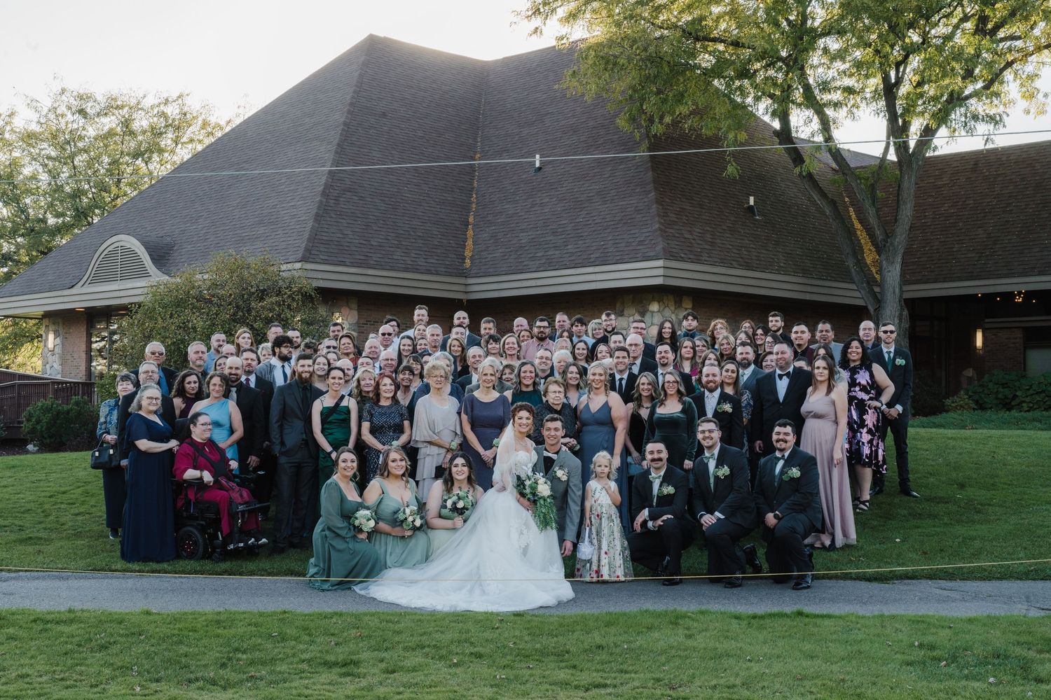Large wedding party group photo gathered outside a modern church building.