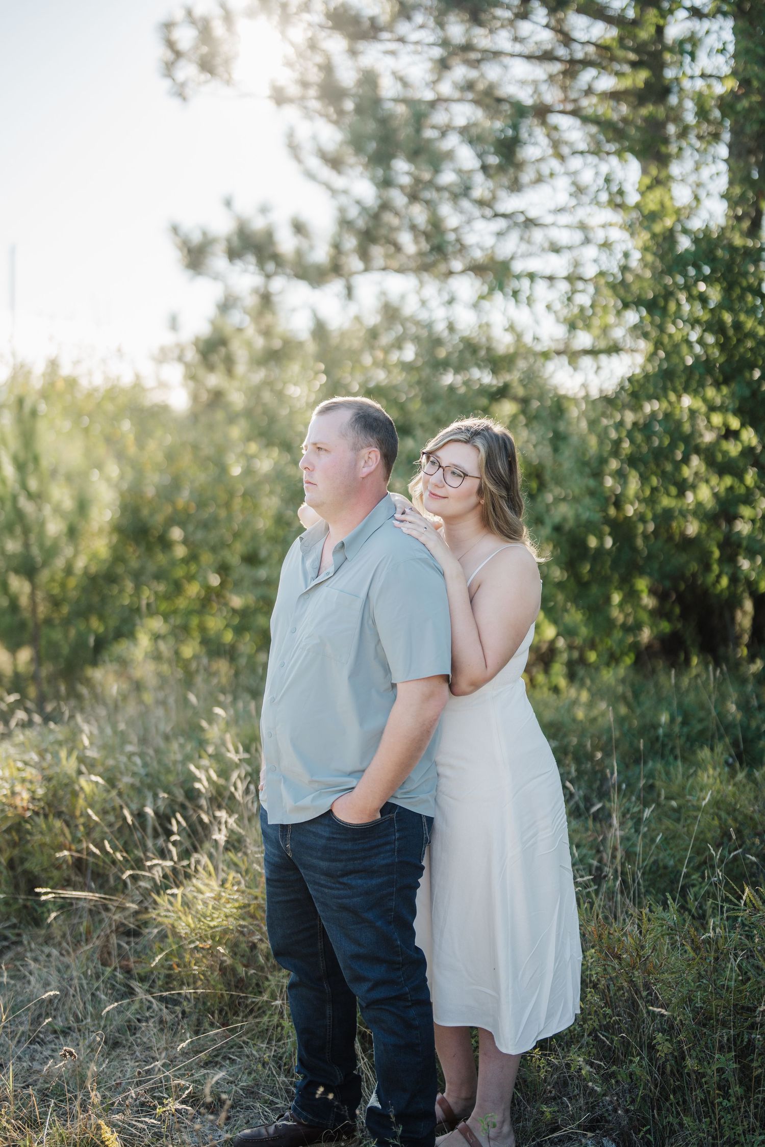 A couple embraces in a sunlit meadow during a romantic outdoor photo session.
