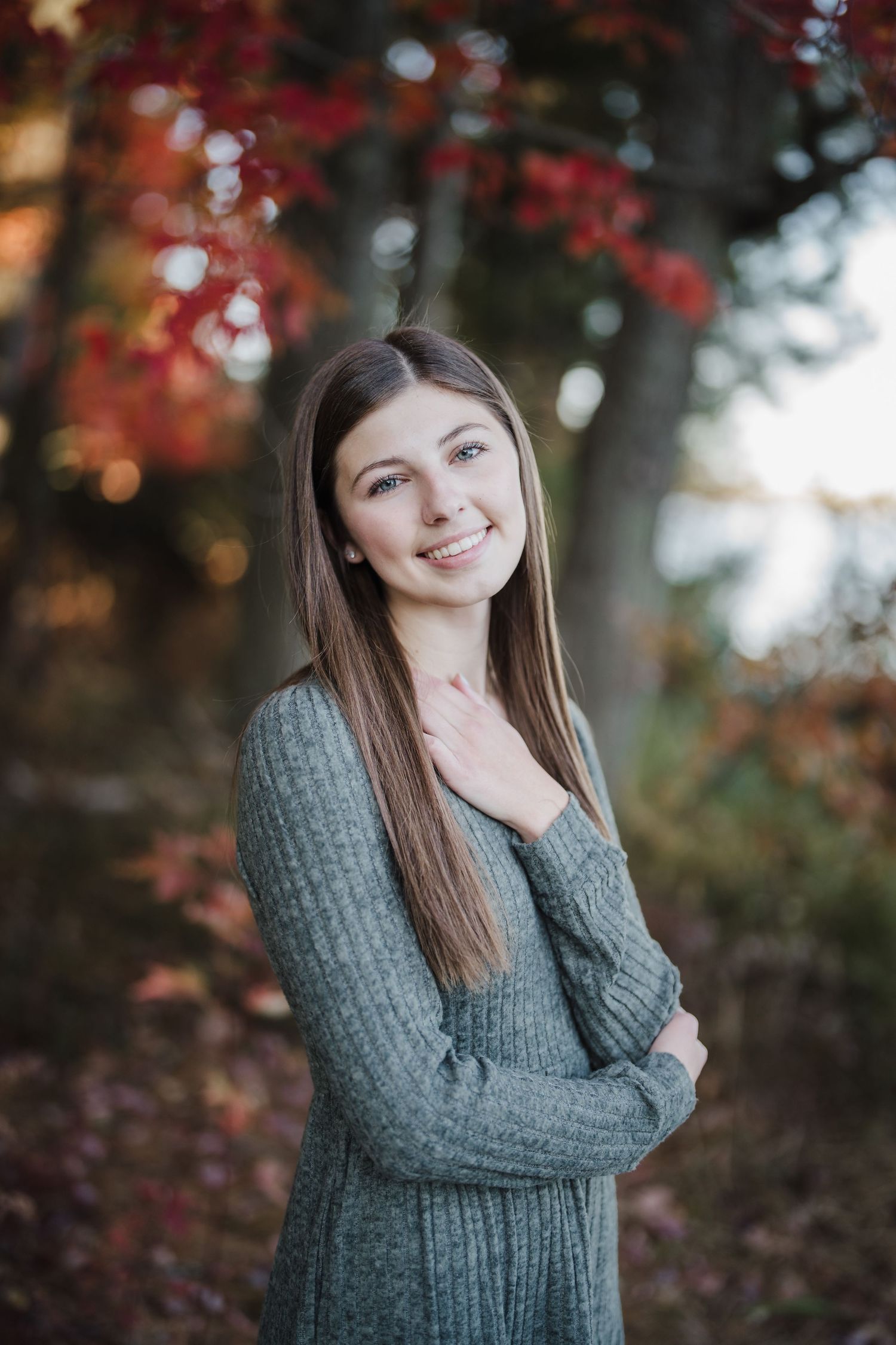 Autumn portrait series with red maple leaves and grey sweater in natural lighting.