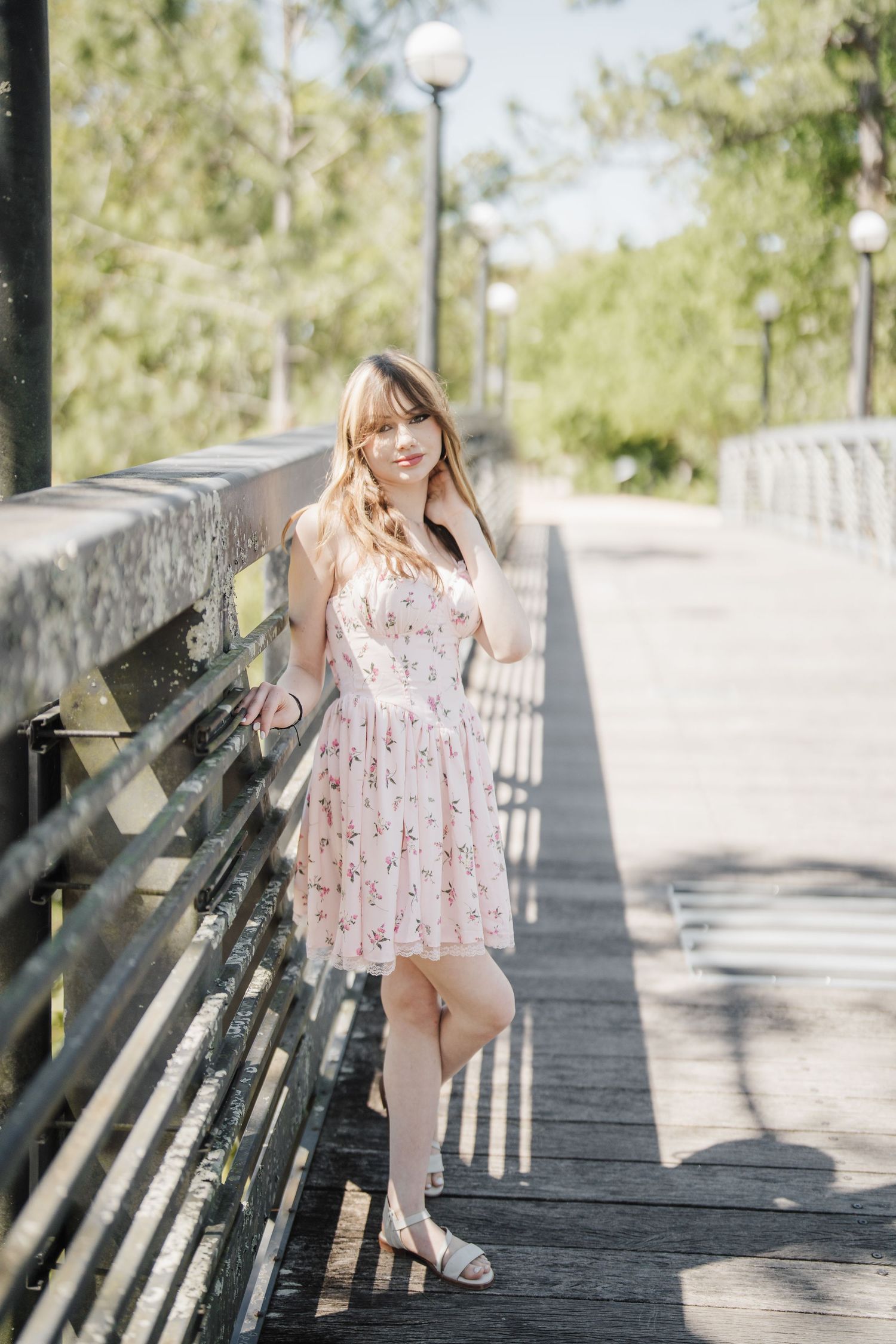 A floral sundress is captured in bright sunlight on a wooden boardwalk with benches.