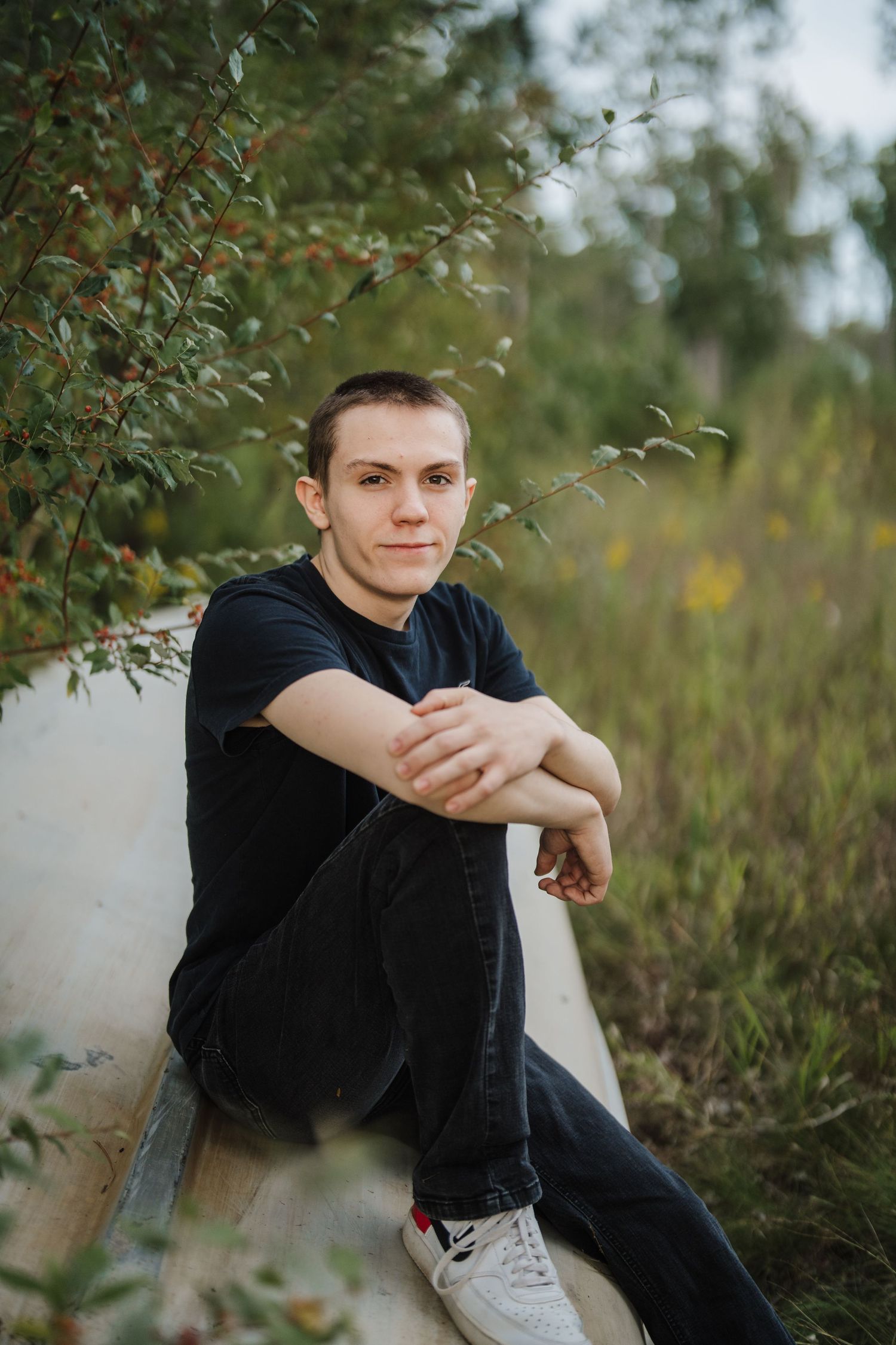 A relaxed outdoor portrait sitting on a white surface surrounded by green foliage.