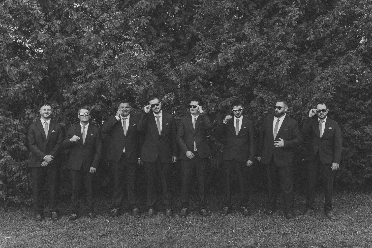 A black and white vintage photograph shows a large group of formally dressed people lined up outdoors.