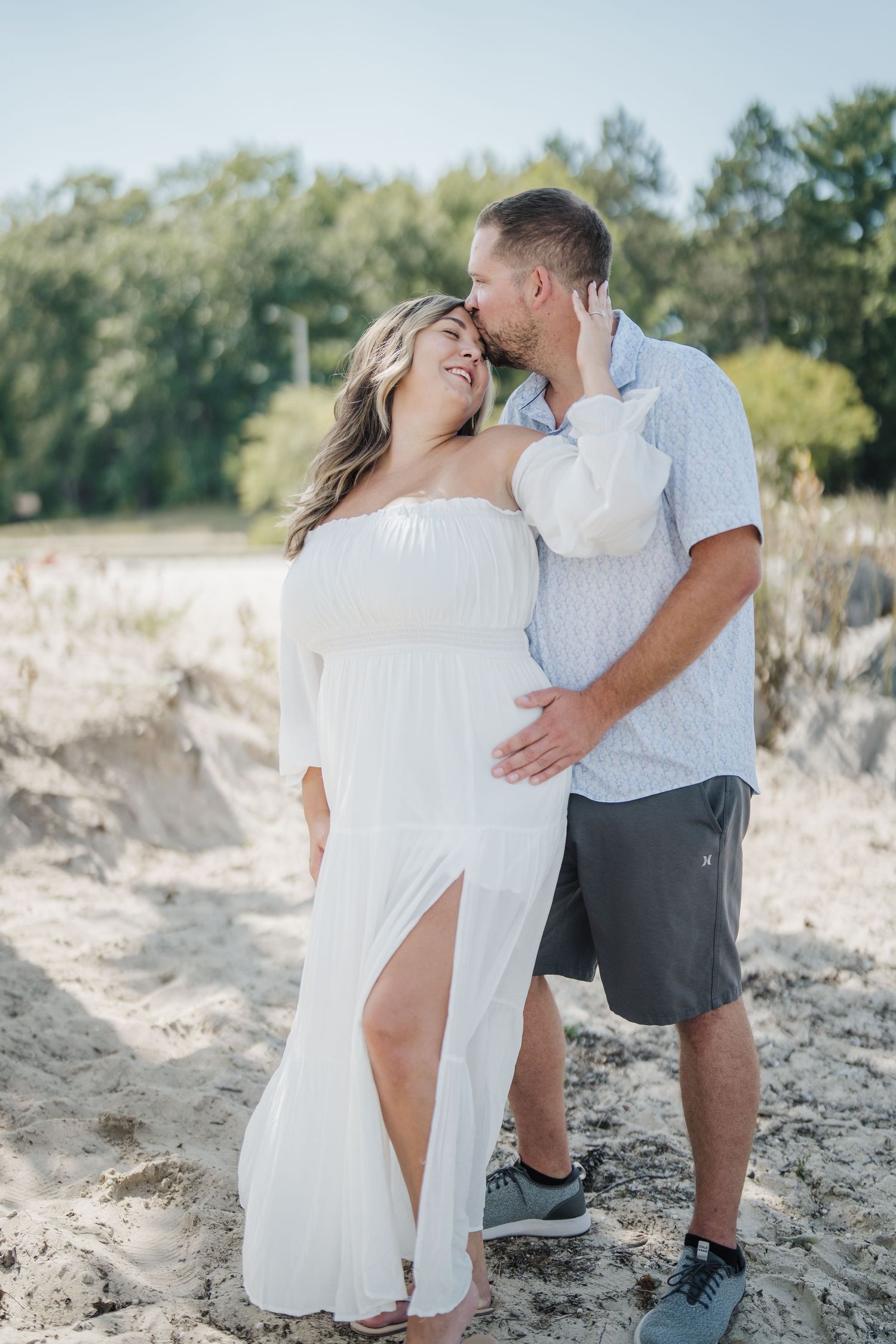 Romantic couple embraces on a sandy beach during a bright summer day.