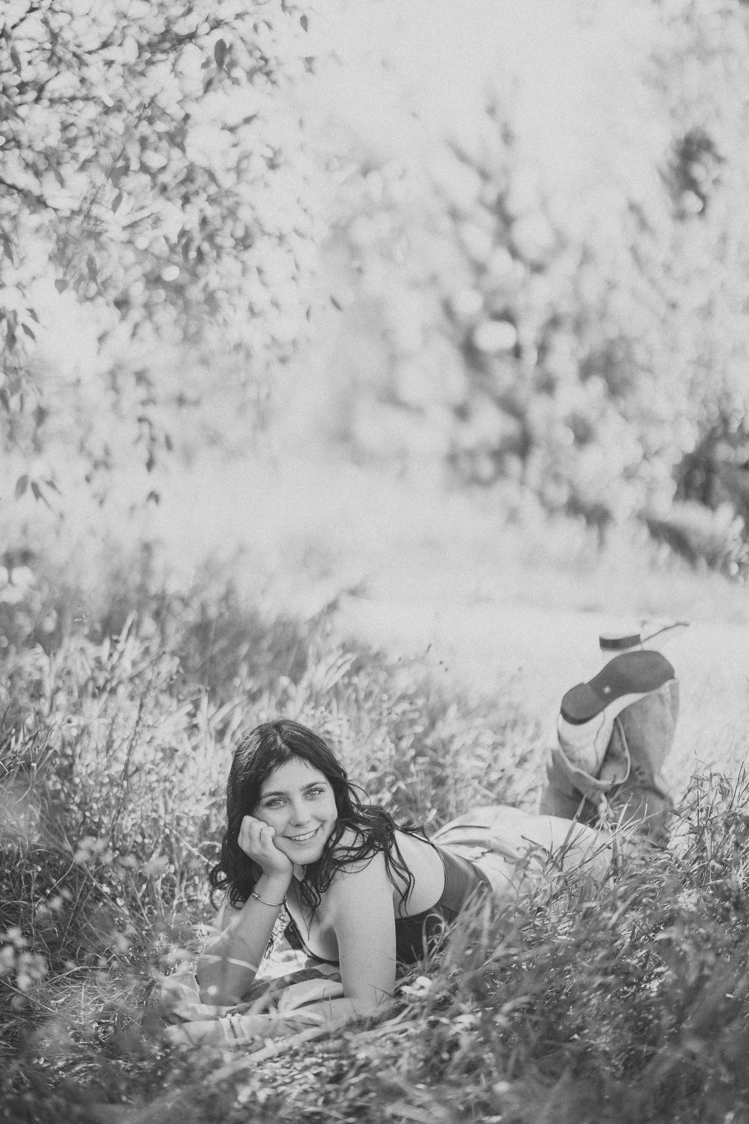 Black and white artistic portrait captured in tall grass with soft natural lighting.