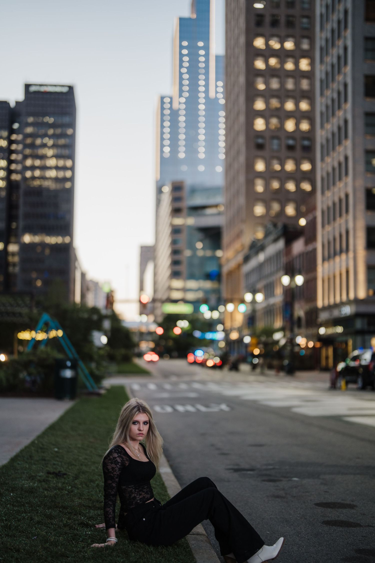 Urban nighttime photoshoot in downtown with city lights and skyscrapers creating a moody atmosphere.