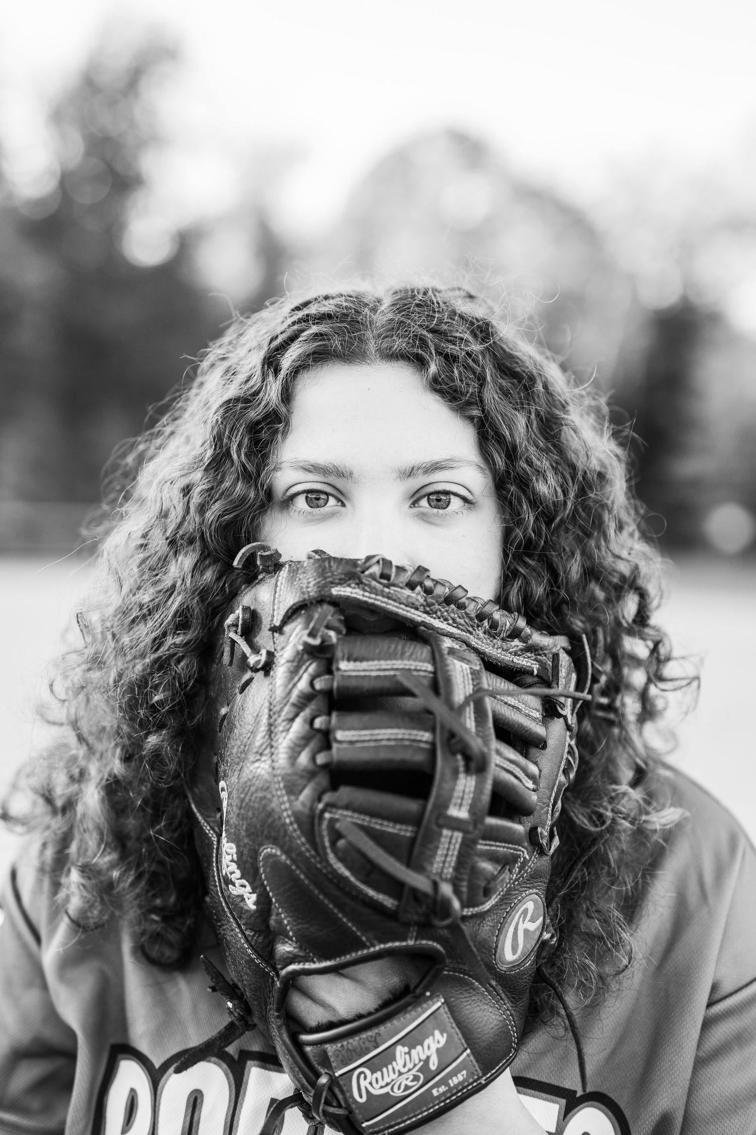 A series of black and white photos showing a baseball player peeking through their glove in different poses.