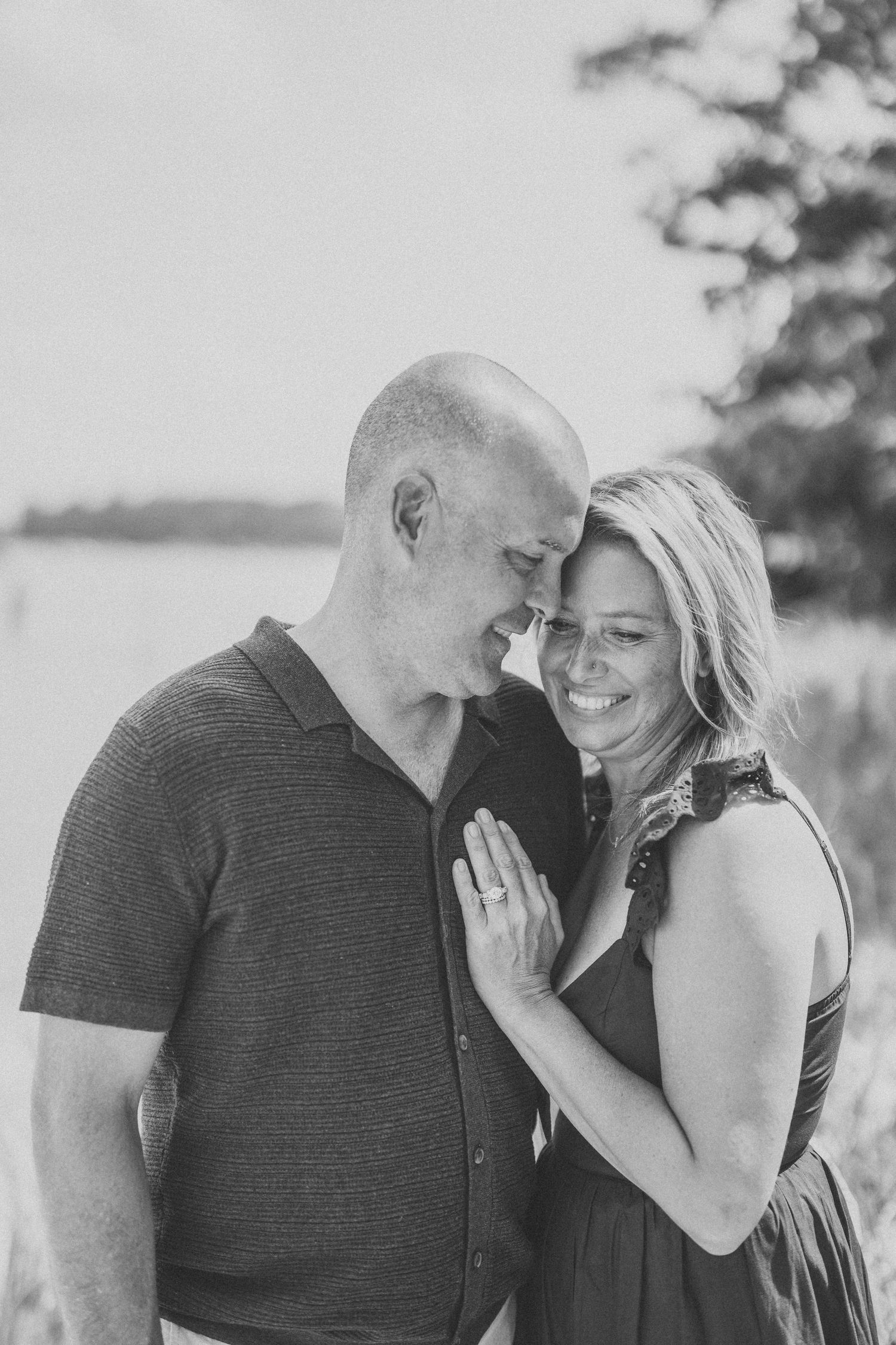 Black and white photo series showing a romantic couple laughing and embracing in a natural outdoor setting.