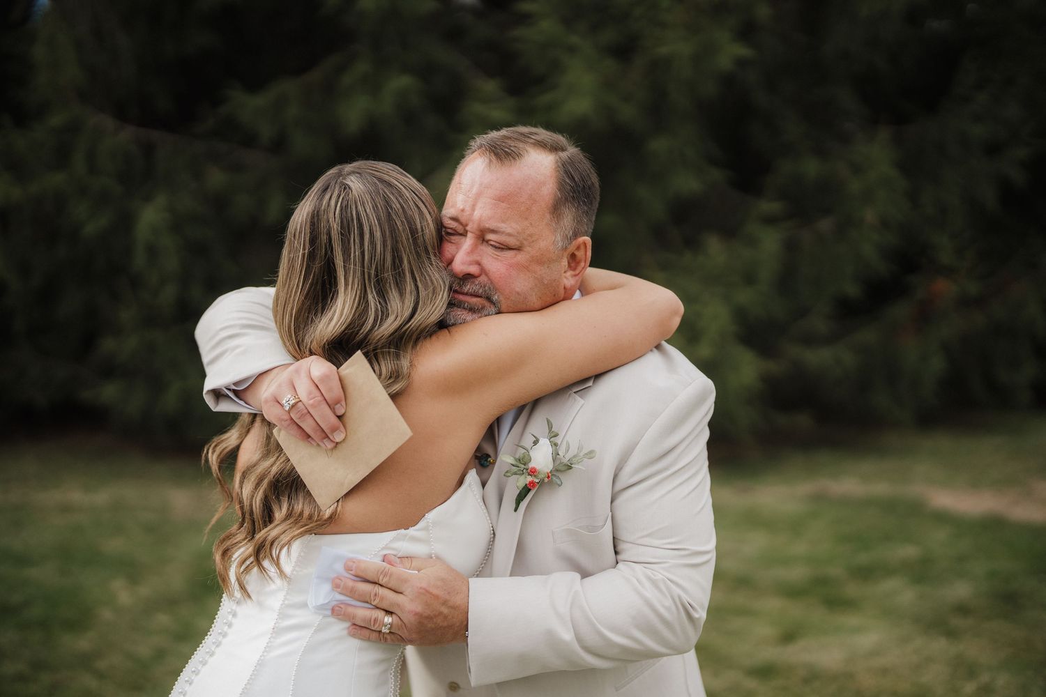 A couple shares an intimate embrace outdoors during their wedding photoshoot in a natural setting.