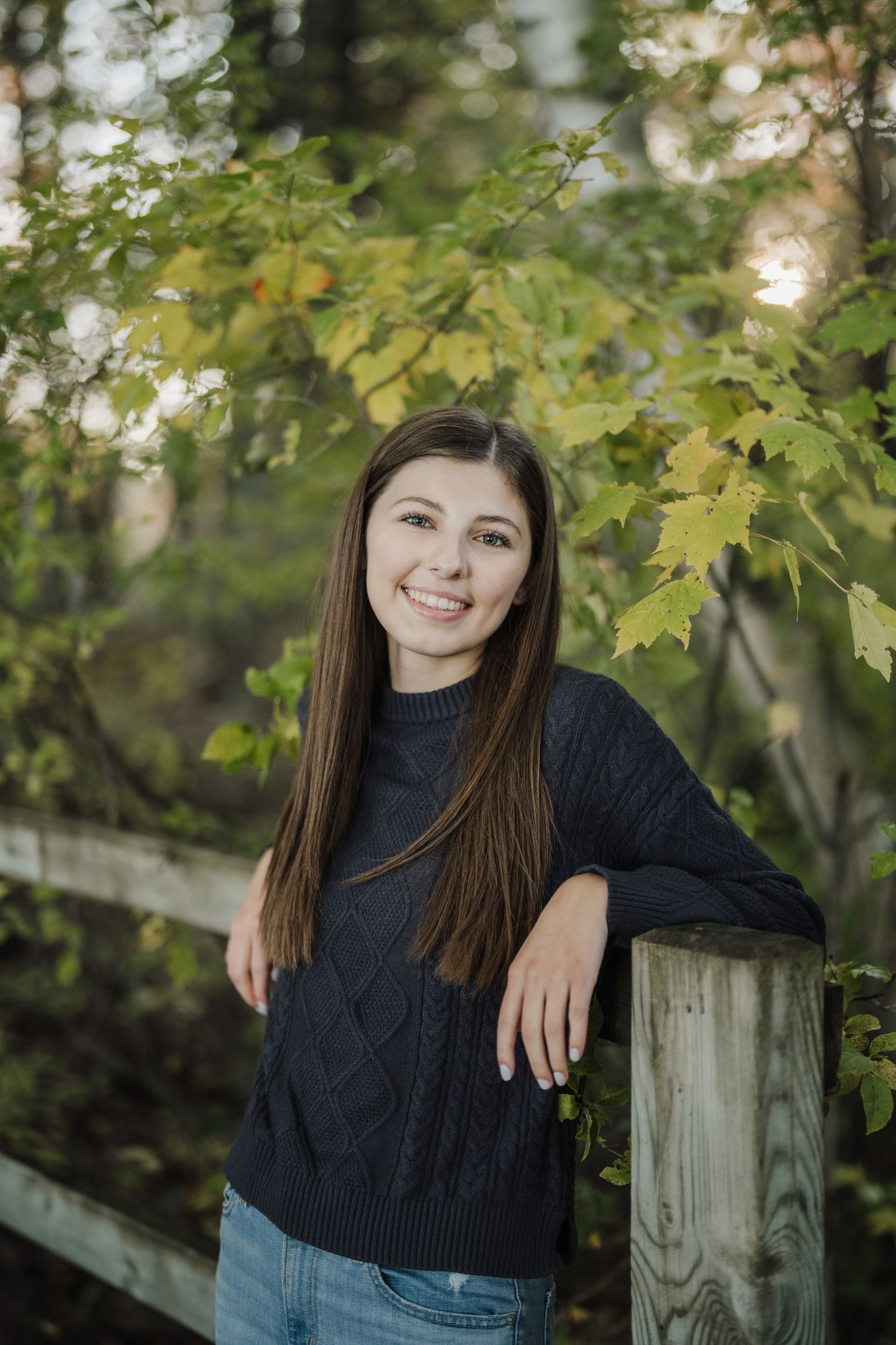 Outdoor portrait series featuring a navy sweater against wooden fence and autumn foliage backdrop.