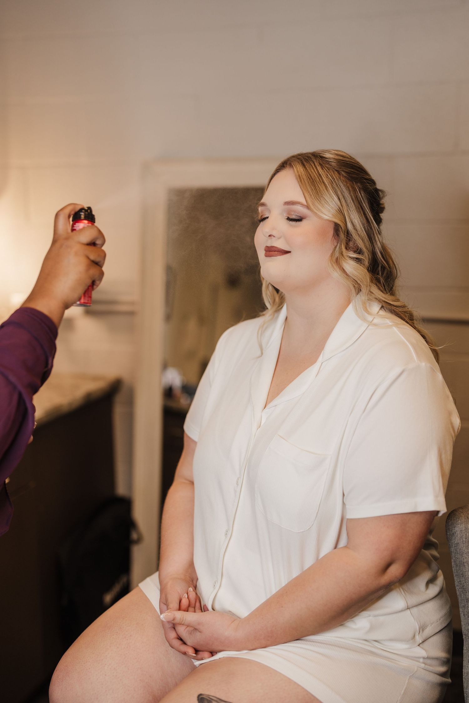 Getting ready scene with final touches of bridal makeup being applied.