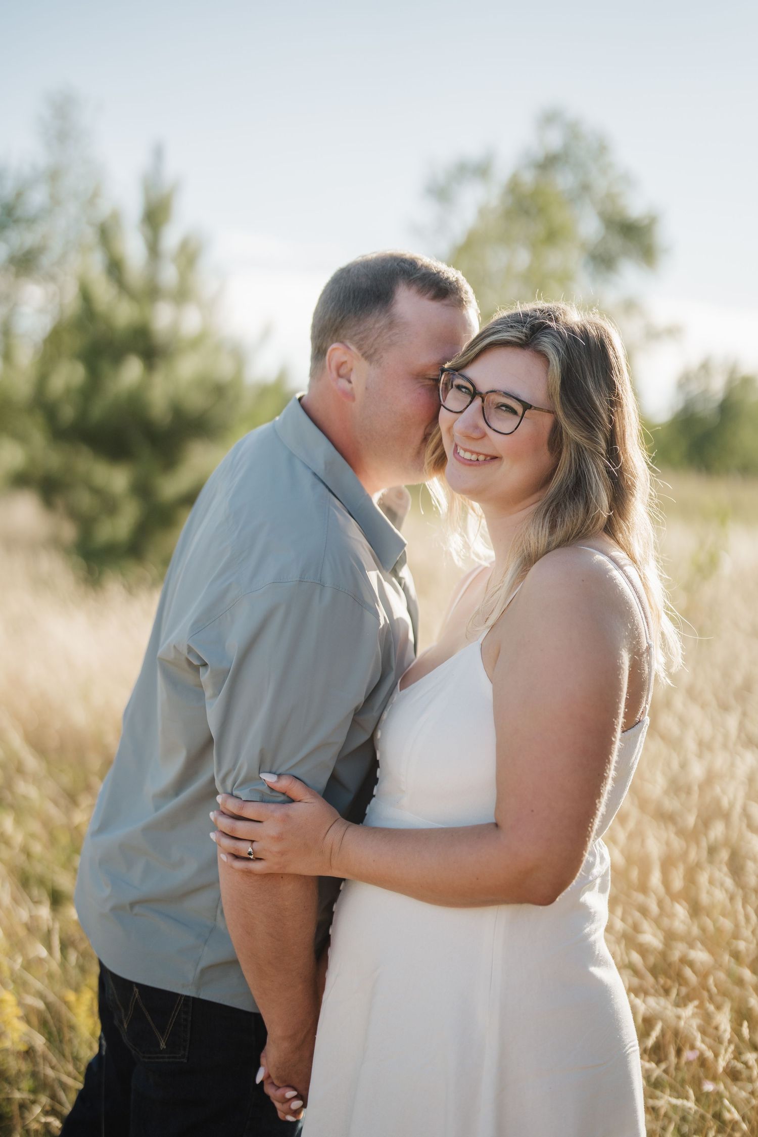 A couple shares intimate moments in a golden wheat field during a romantic outdoor photoshoot at sunset.