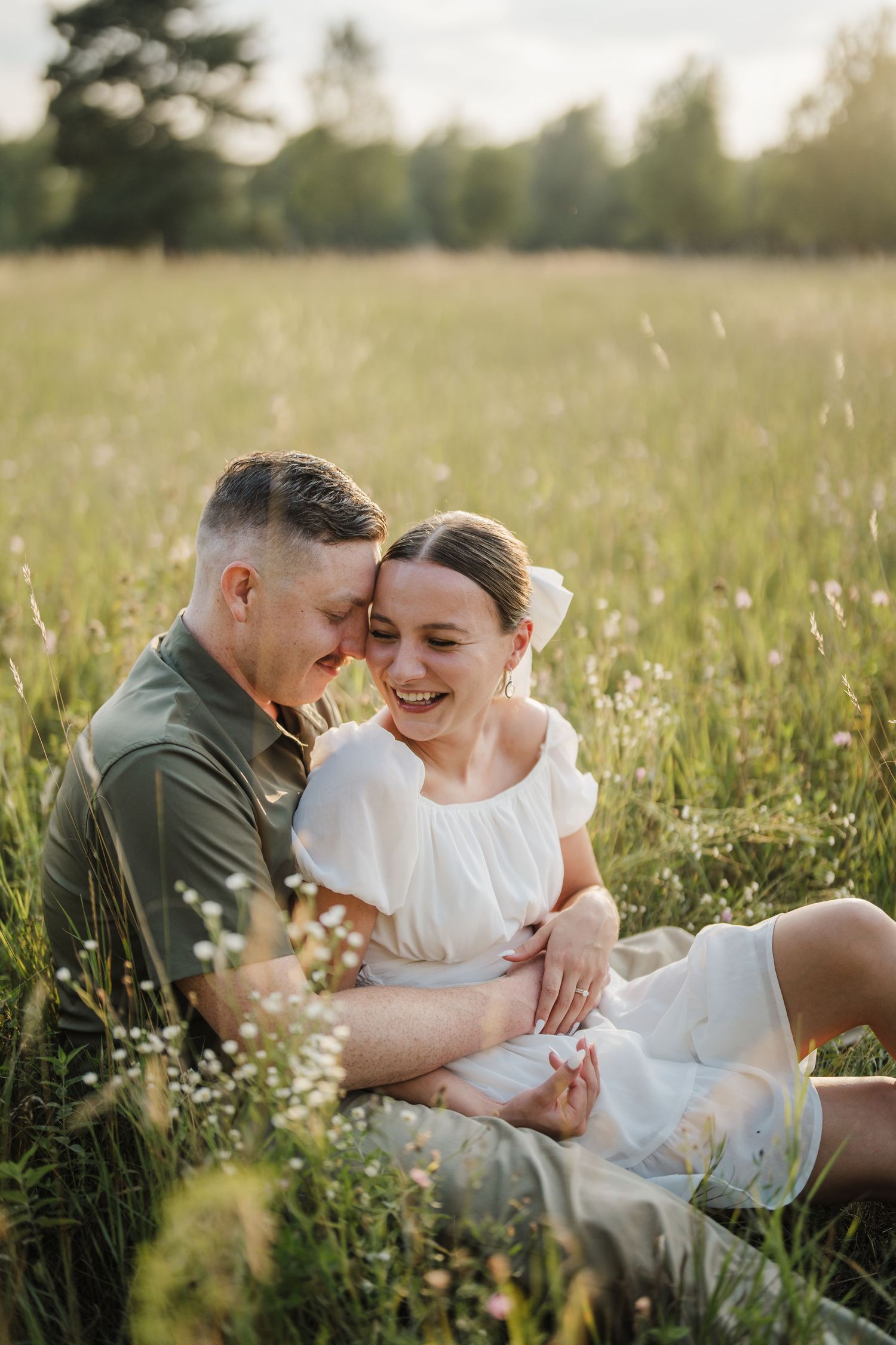 Couple sharing intimate moments while laying in a sunny wildflower meadow during golden hour.