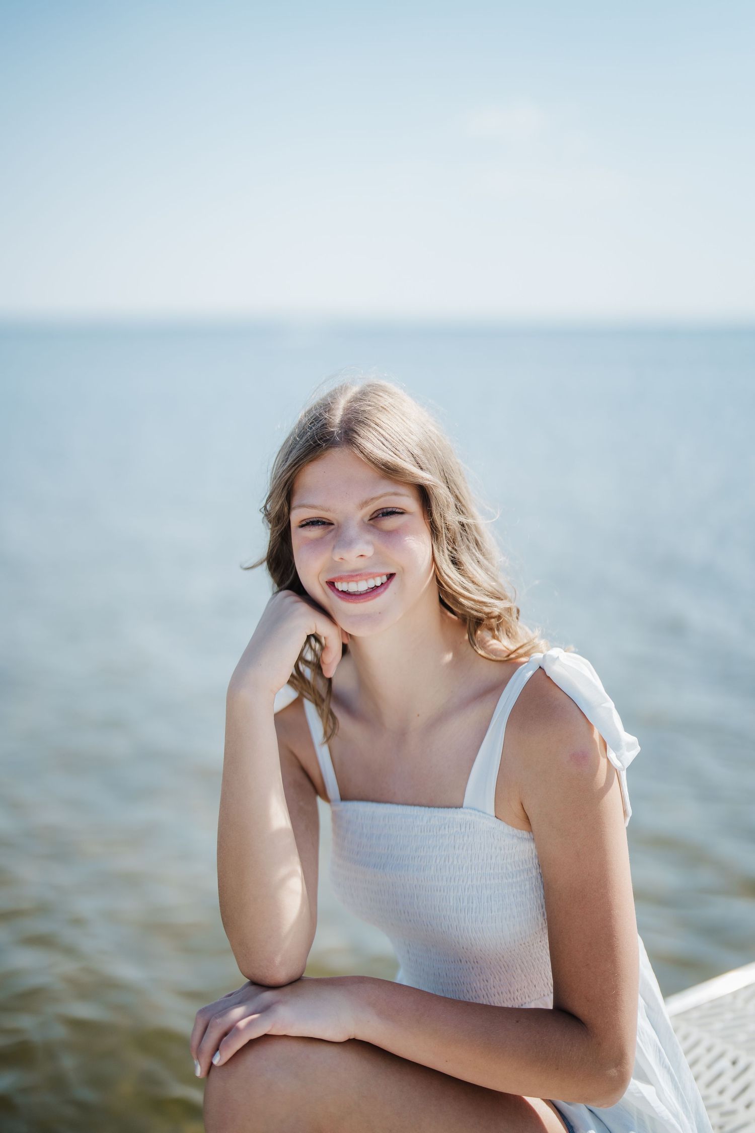 Candid seaside portrait showing joyful expressions against a bright blue ocean backdrop.