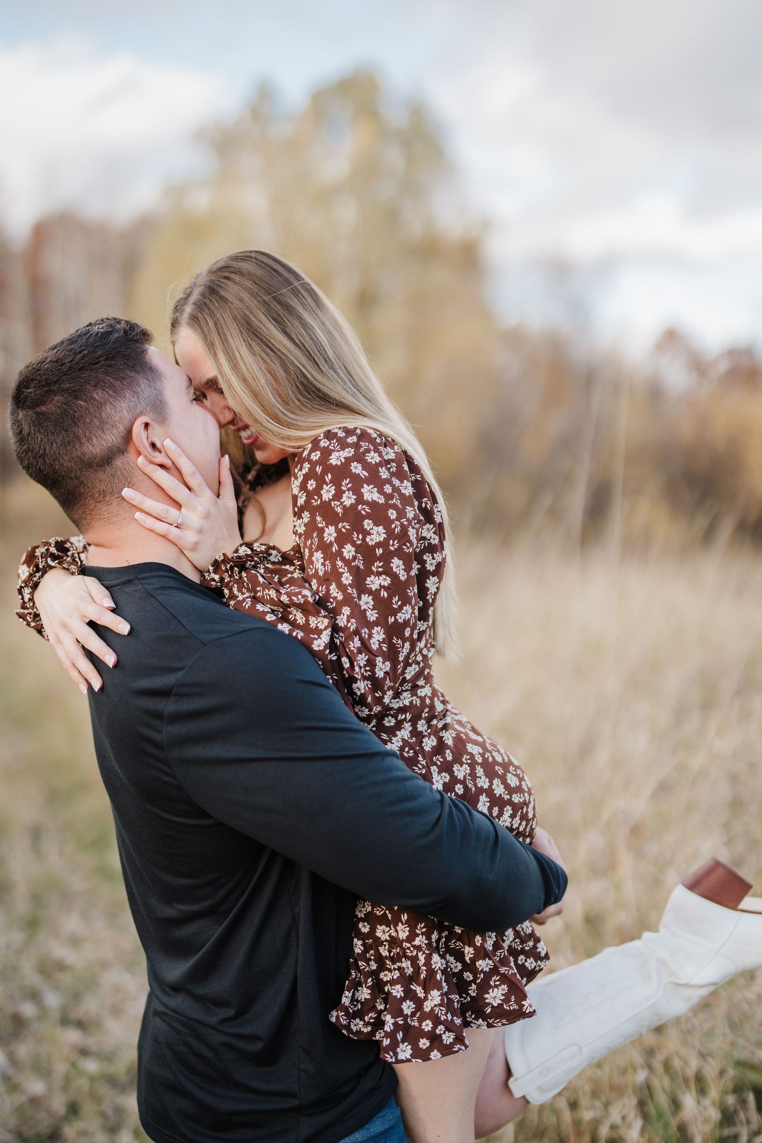 A couple embraces in a field of tall grass during a romantic proposal moment in autumn.