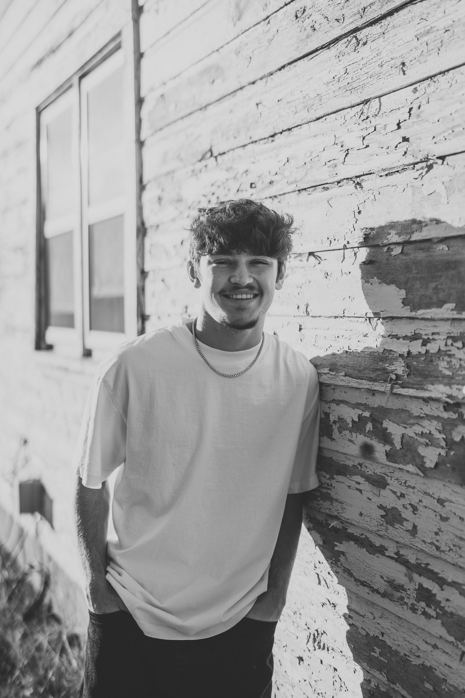 Black and white portrait against weathered white wall background.