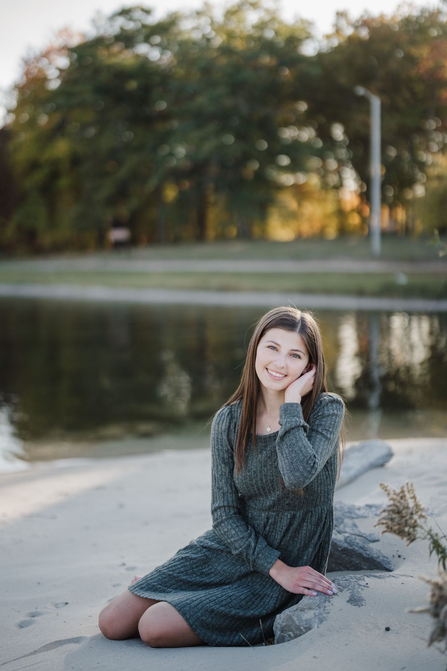 A person in a cozy gray sweater dress poses gracefully on a sandy beach during golden hour.