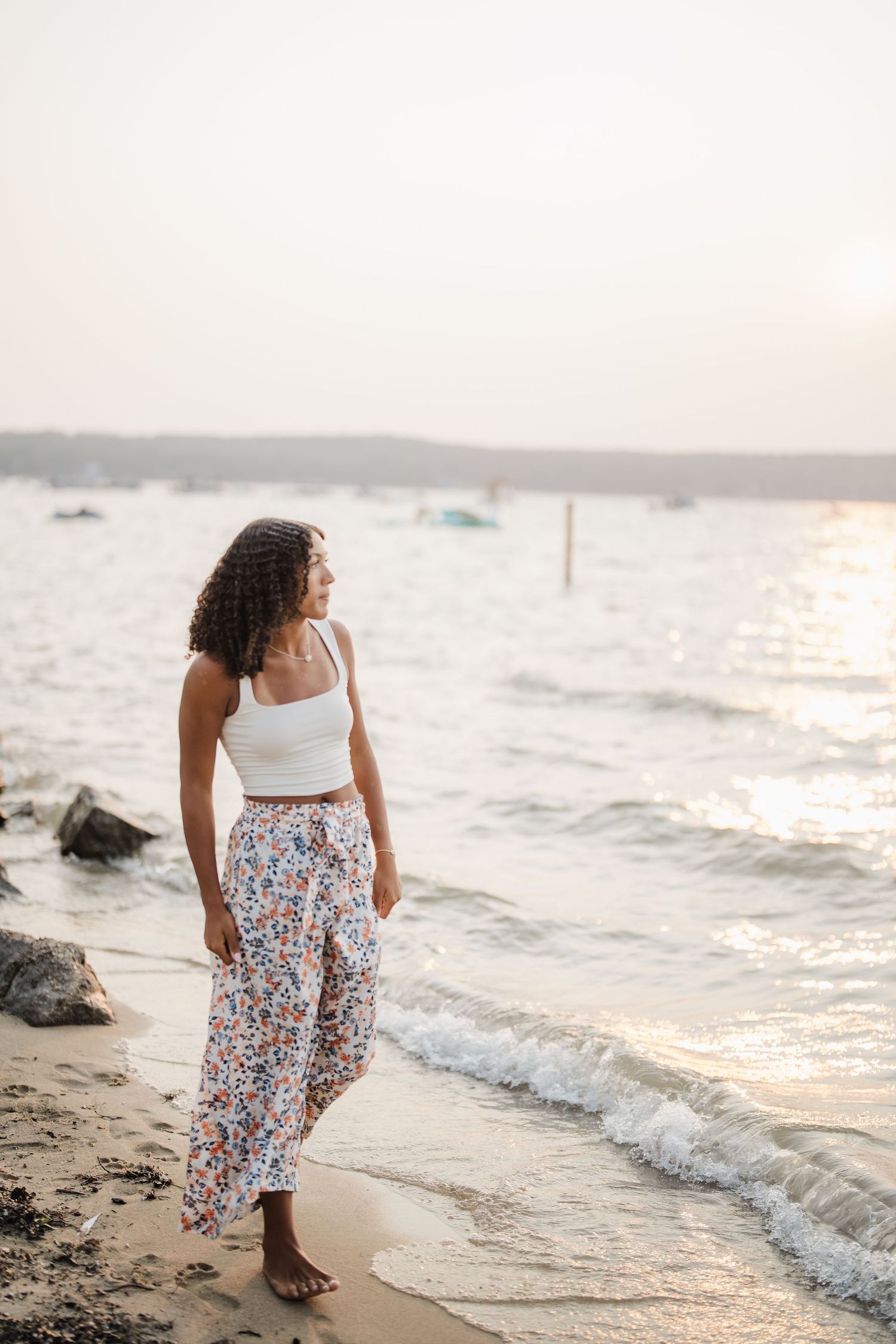 Beachside portrait session at sunset featuring a floral skirt and white top along the shoreline.