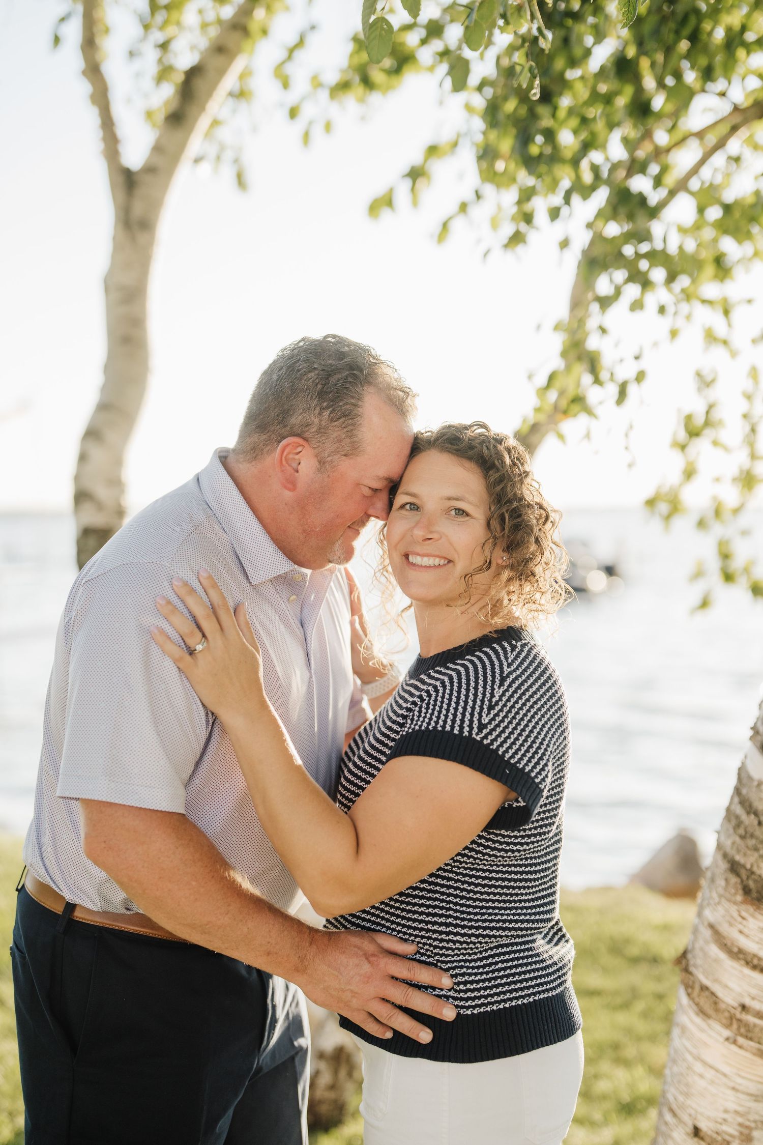 A couple in love shares tender moments in a series of romantic outdoor photos under sunlit trees.