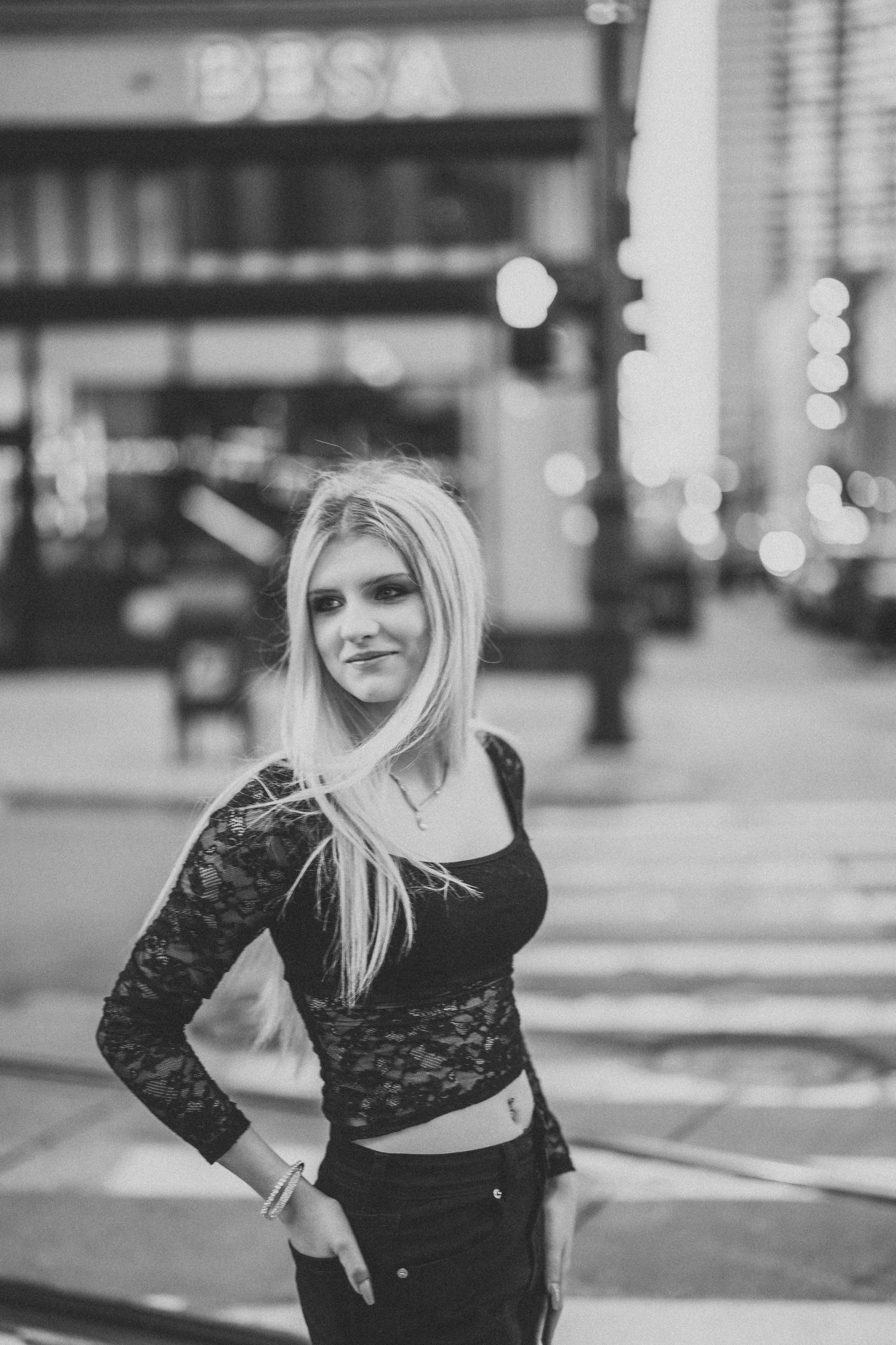 Black and white fashion portraits showing dynamic poses and movement in a city street with bokeh lights.