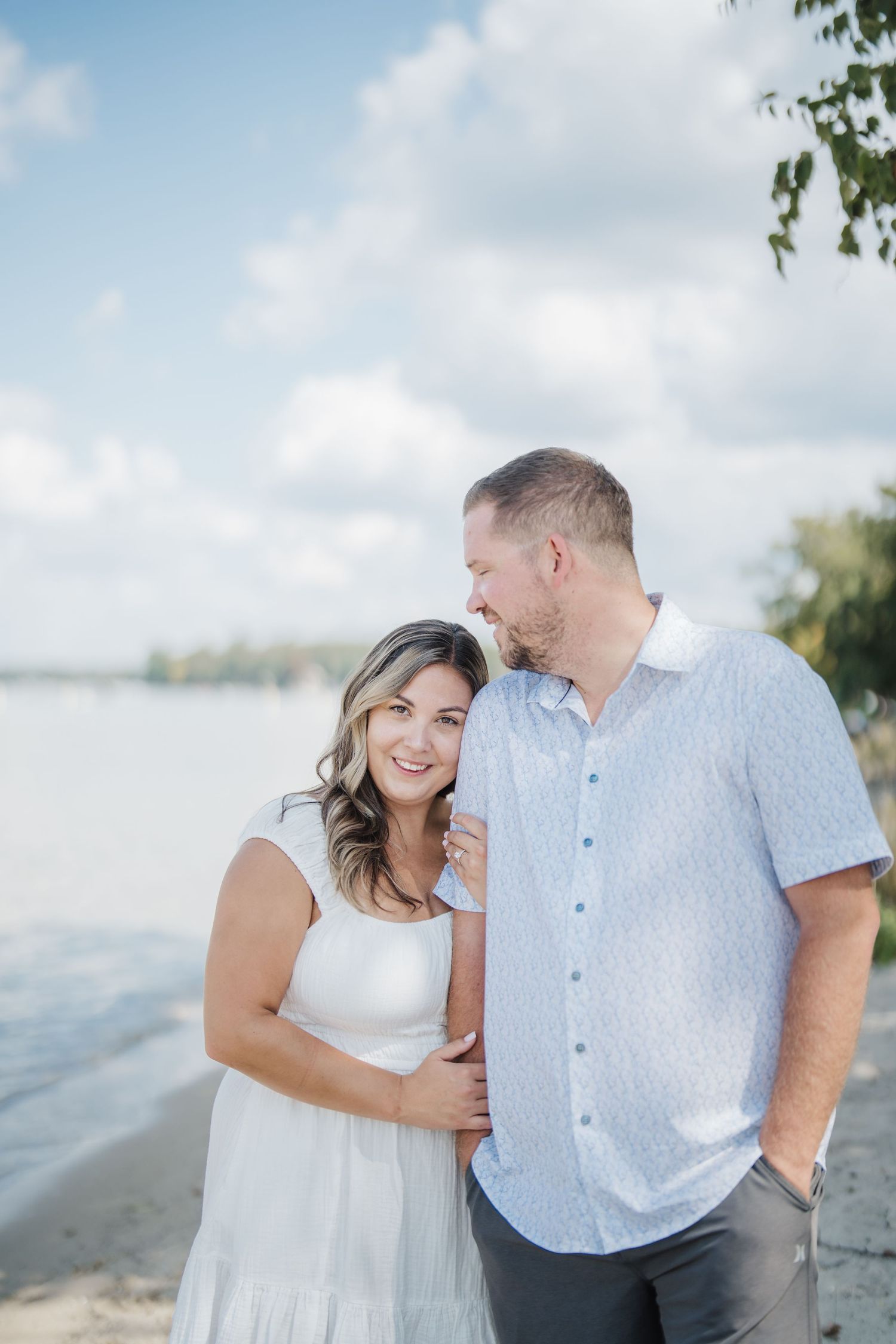 A couple shares tender moments together during a lakeside photoshoot on a bright summer day.