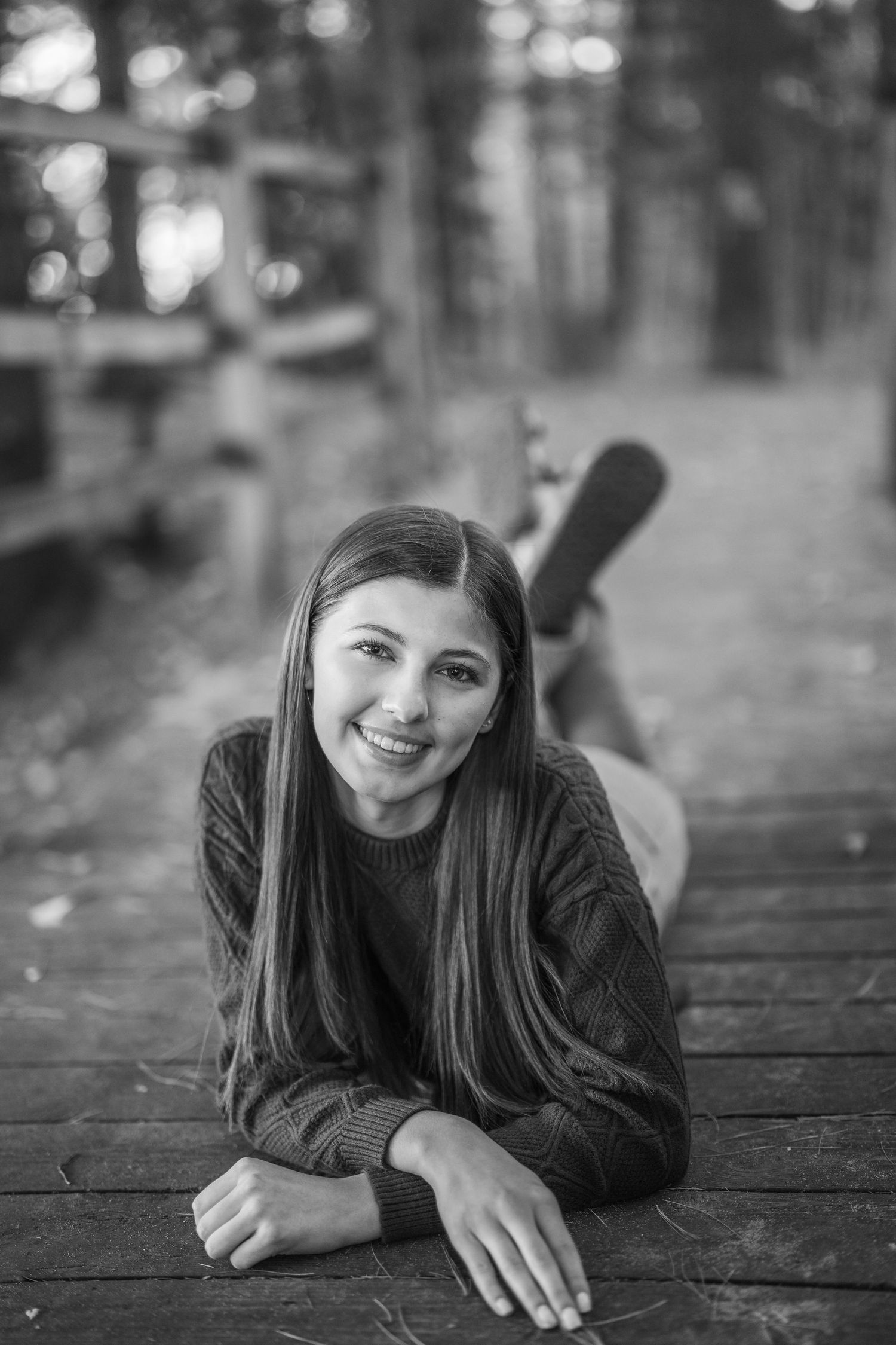 A series of black and white portraits showing someone lying on a wooden deck in casual poses with natural lighting.