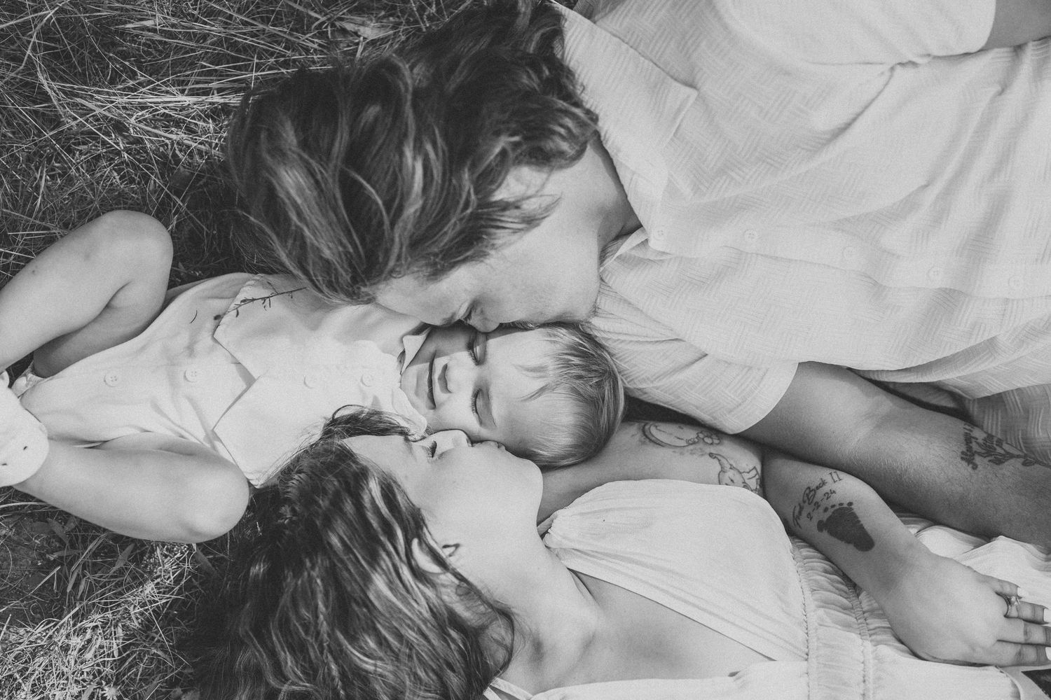A series of intimate black and white photographs showing tender moments between parent and child lying down.