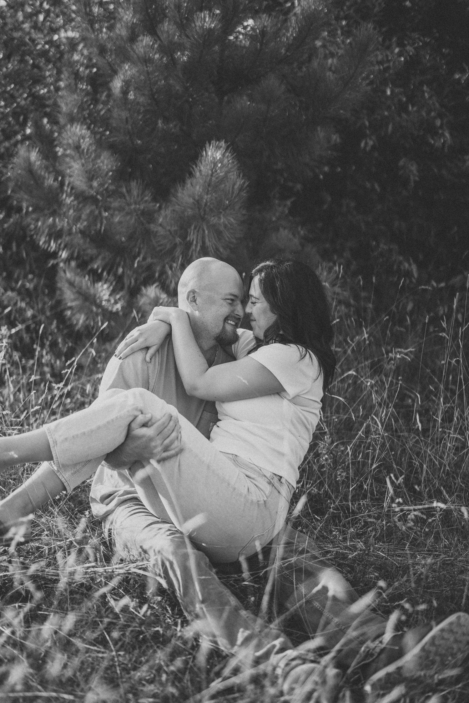 A romantic black and white photo sequence shows a couple lying in a meadow of tall grass and wildflowers.