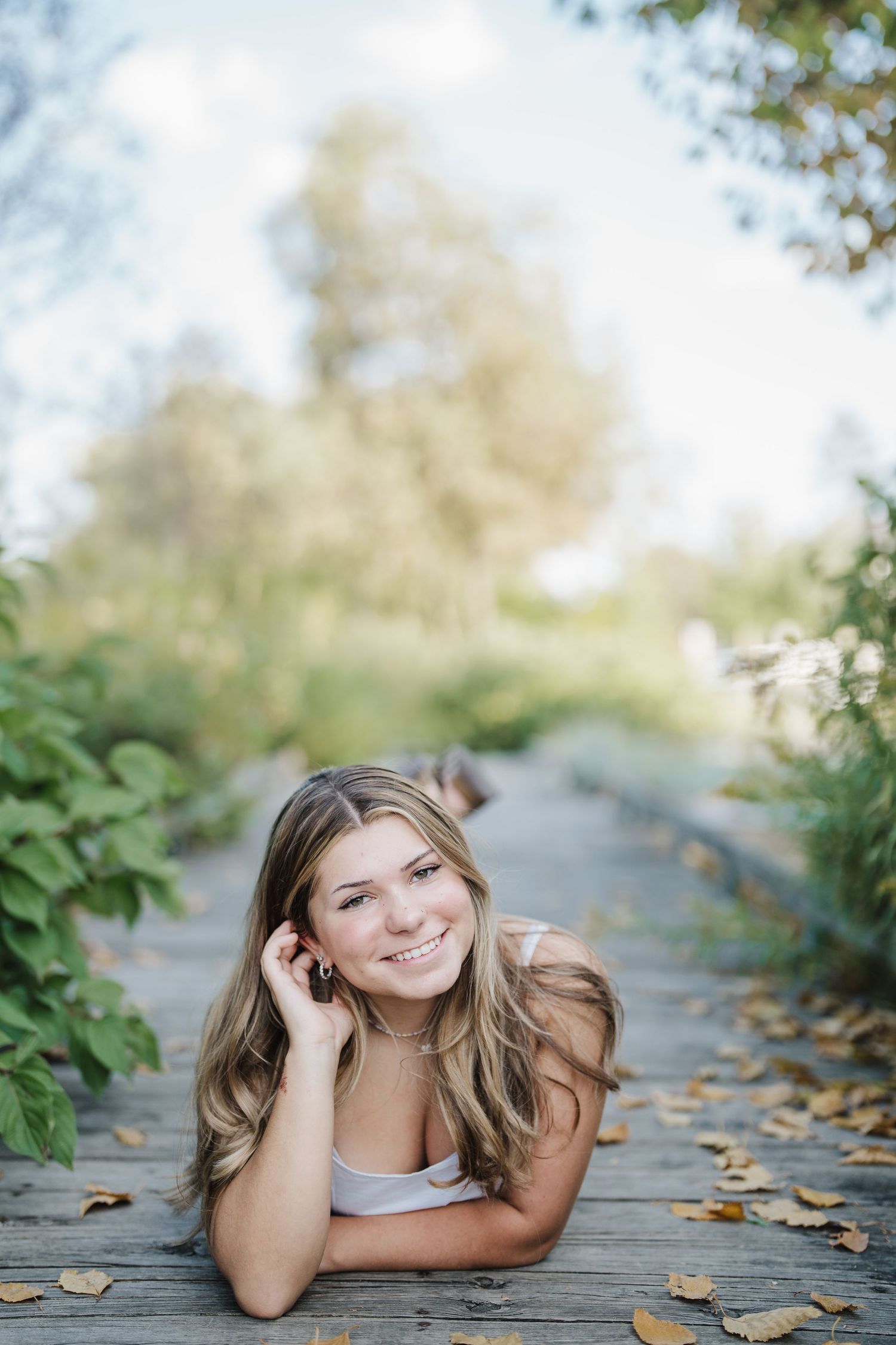 Autumn portrait series with fallen leaves on a wooden walkway in soft natural lighting.