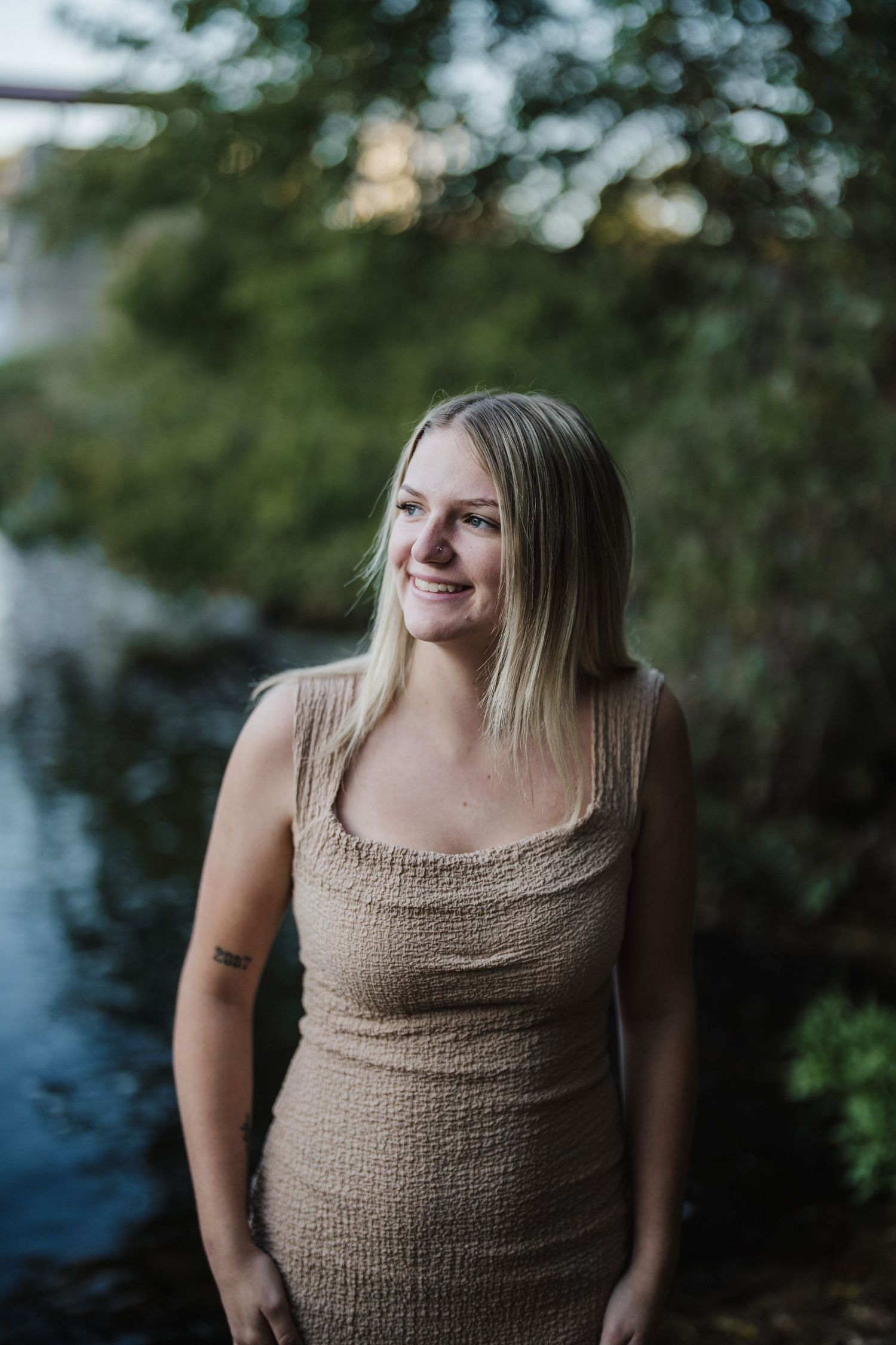 Portrait series of someone in a beige tank top against a blurred natural background.