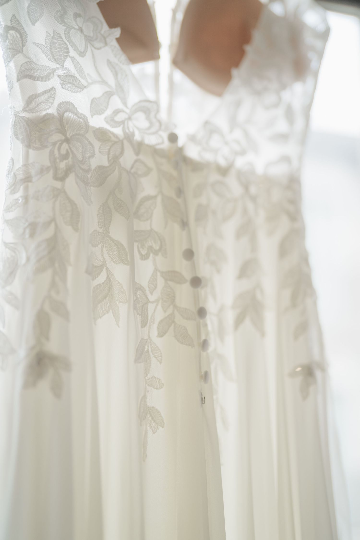 White wedding dresses with delicate lace details hanging on display in a bridal boutique.