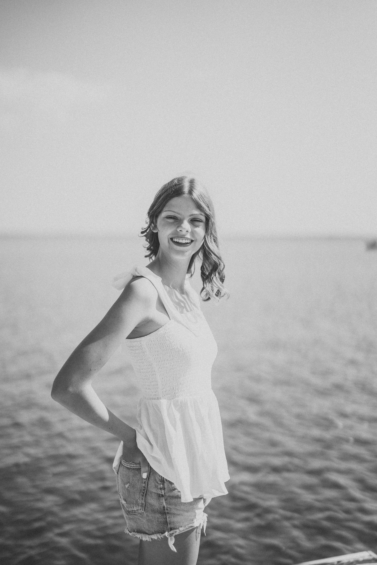 Black and white beach portrait capturing carefree moments against a serene water landscape.