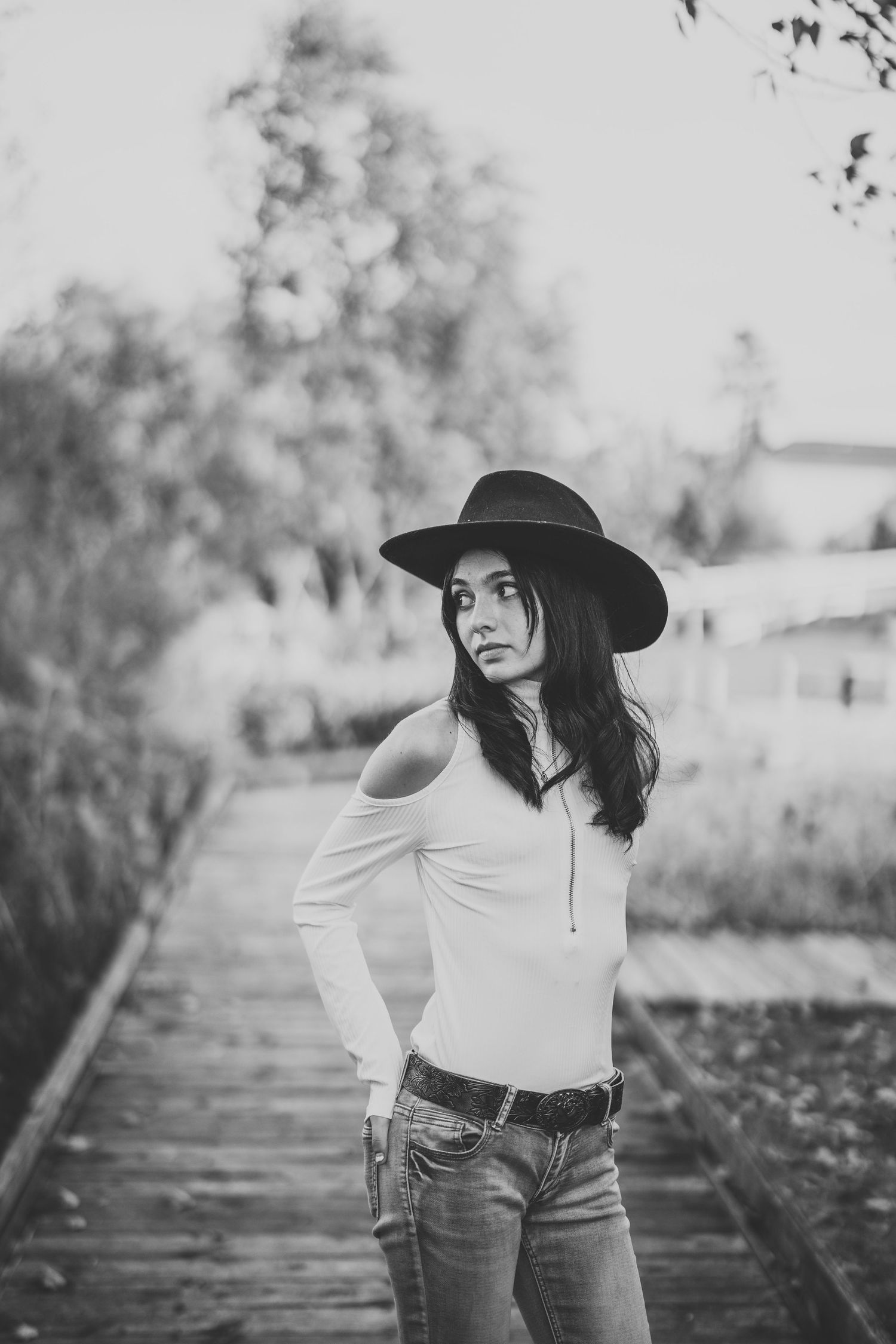 Black and white portrait series of someone wearing a wide brim hat and casual attire in an outdoor setting.