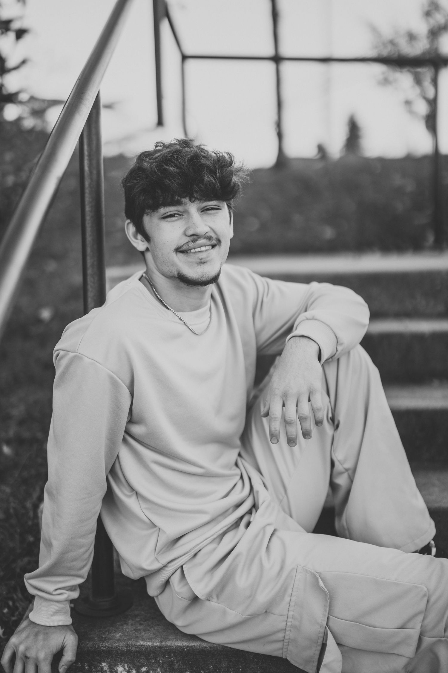 Black and white portrait series showing a person relaxing on bleacher steps in casual clothing.
