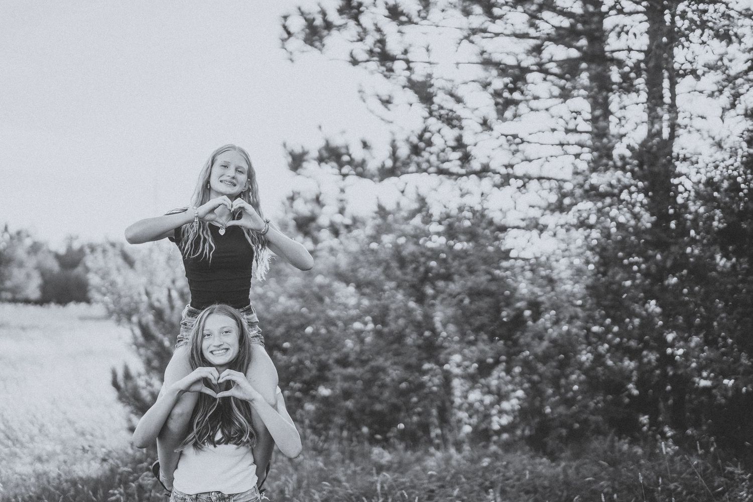 A series of five black and white photos showing joyful outdoor moments with people playing and embracing in nature.