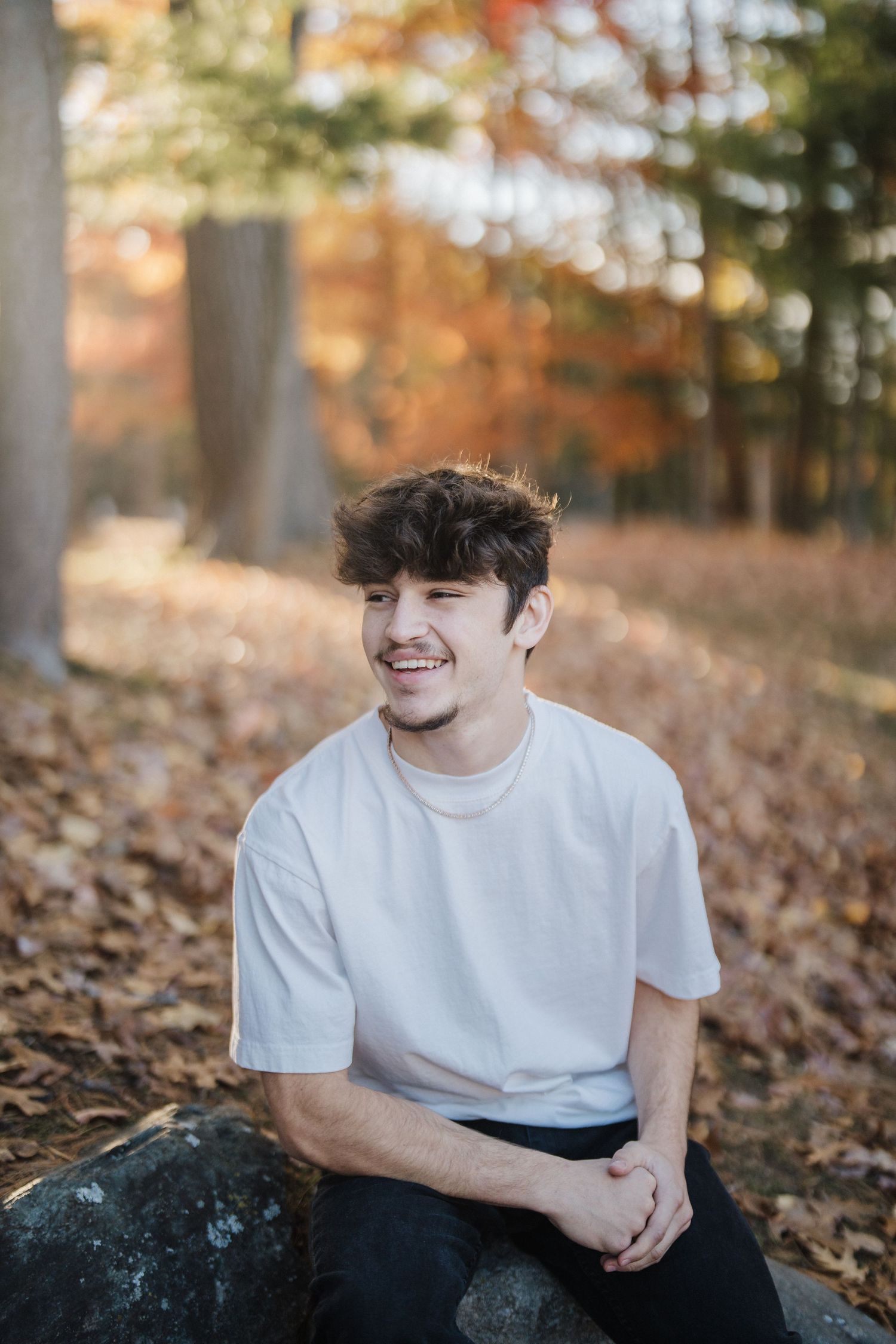 A casual outdoor portrait session in autumn with fallen leaves and natural lighting.