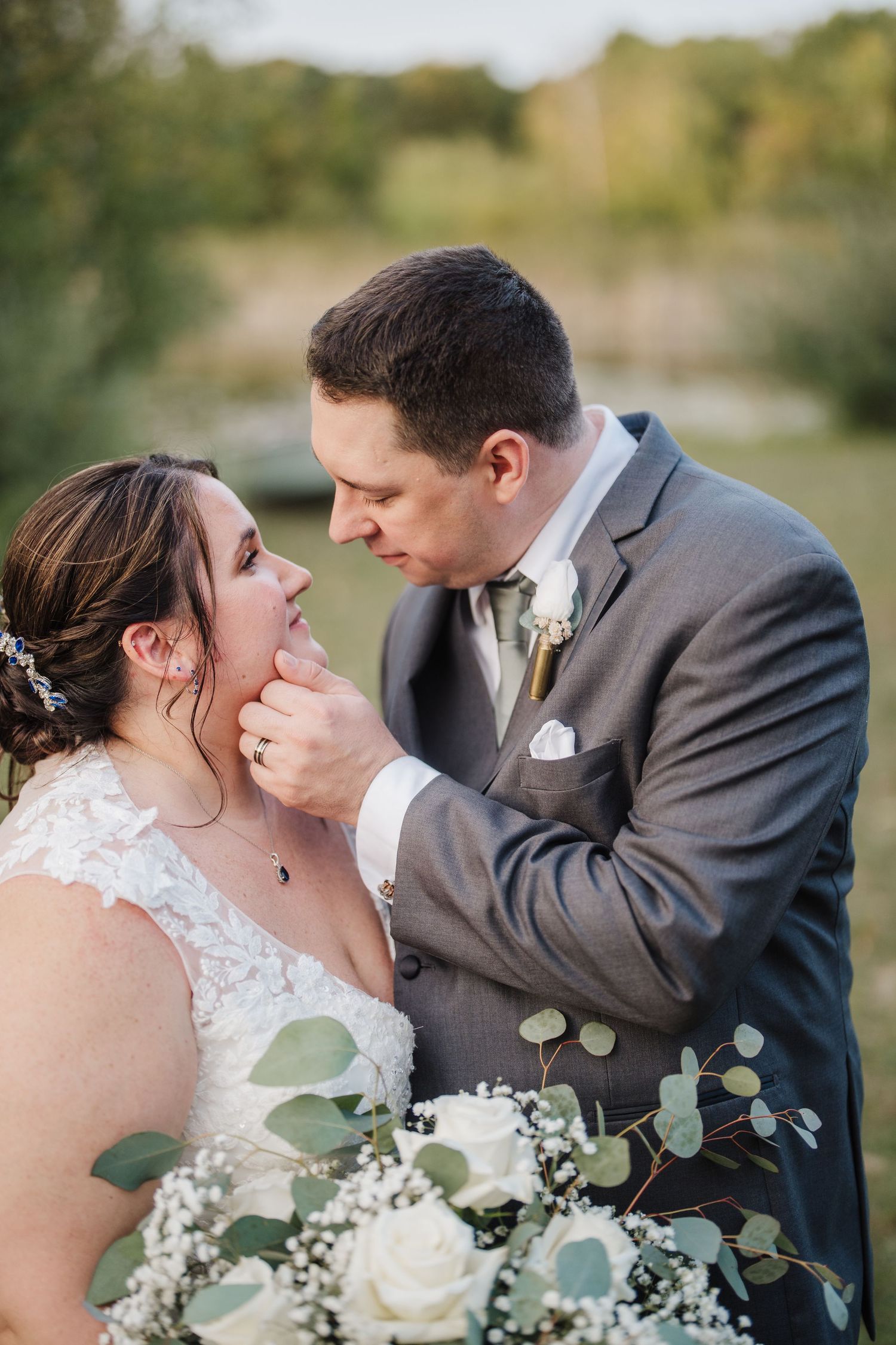 A romantic wedding portrait shows a couple sharing an intimate moment with a floral bouquet in the foreground.