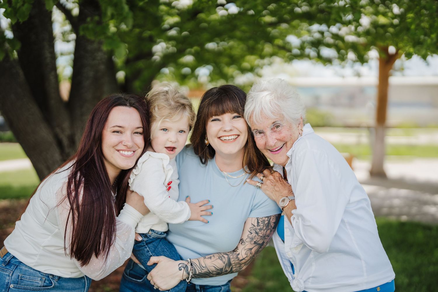 A multigenerational family shares joyful moments together outdoors on a sunny day in a park setting.