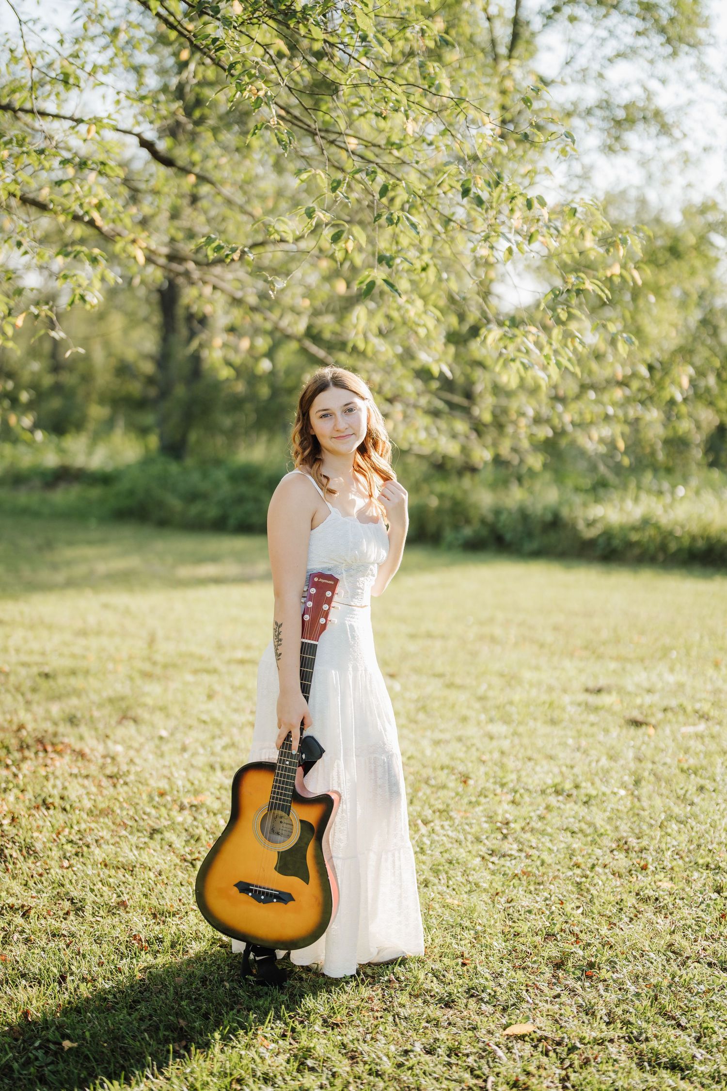 White sundress and acoustic guitar create dreamy summer scene in sunlit meadow.