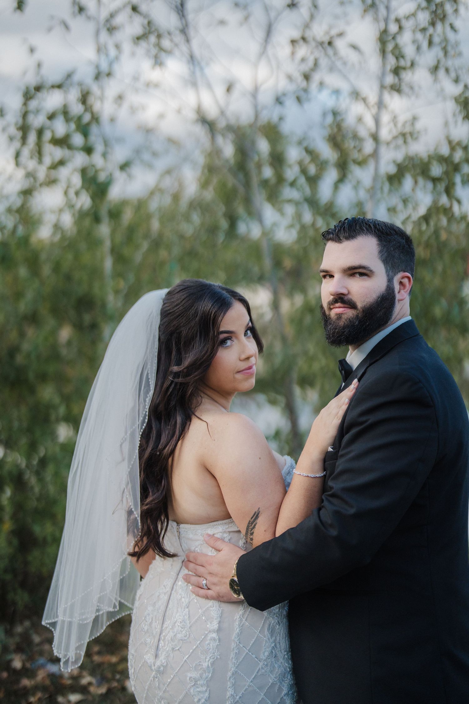 A couple shares intimate moments during their wedding photoshoot against a backdrop of willow trees.
