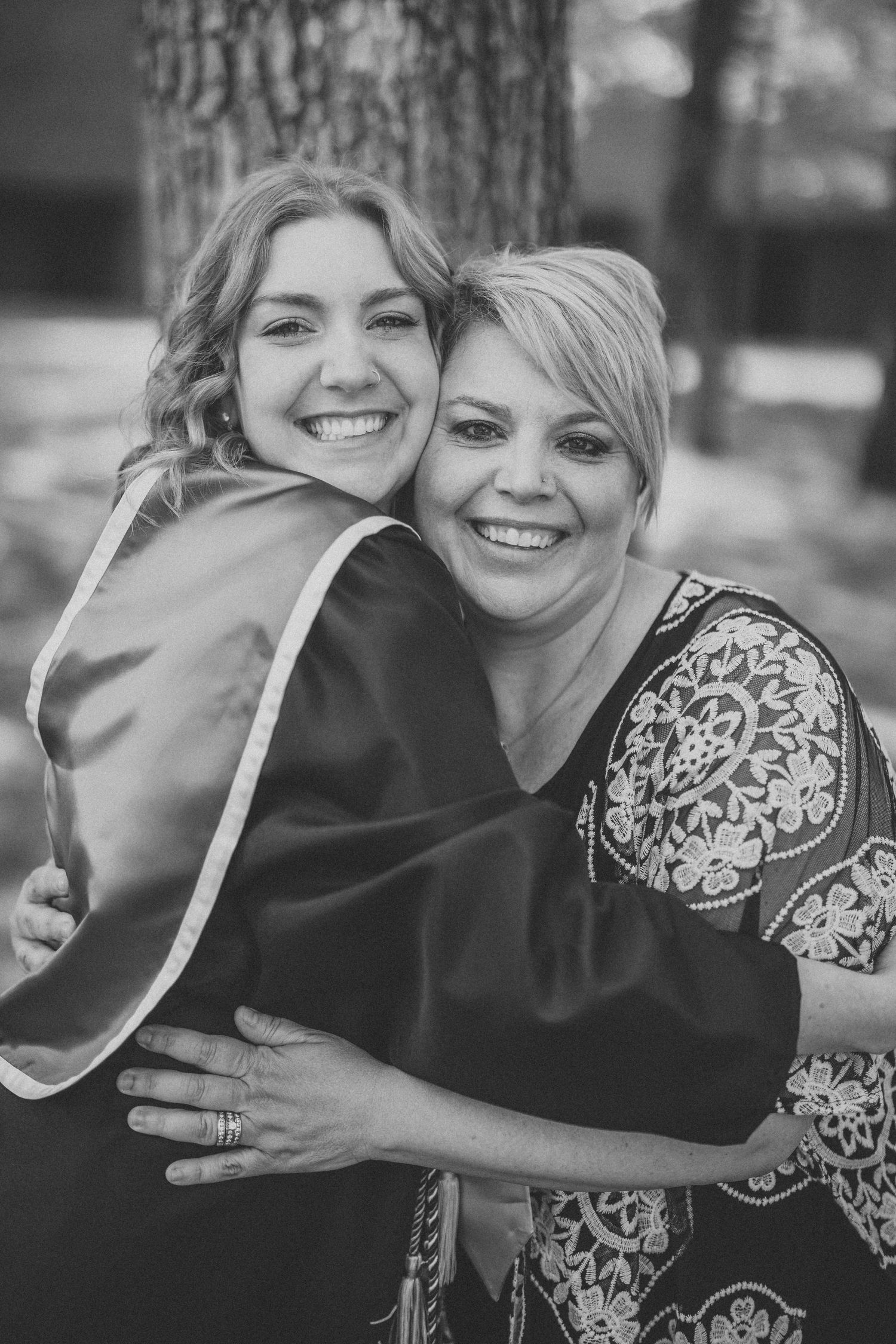 A black and white portrait of two people embracing and smiling warmly at the camera.