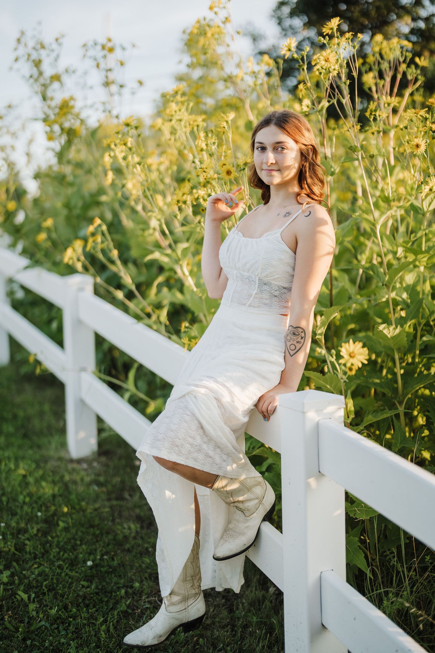 A dreamy summer portrait featuring a white dress and fence amid golden wildflowers.