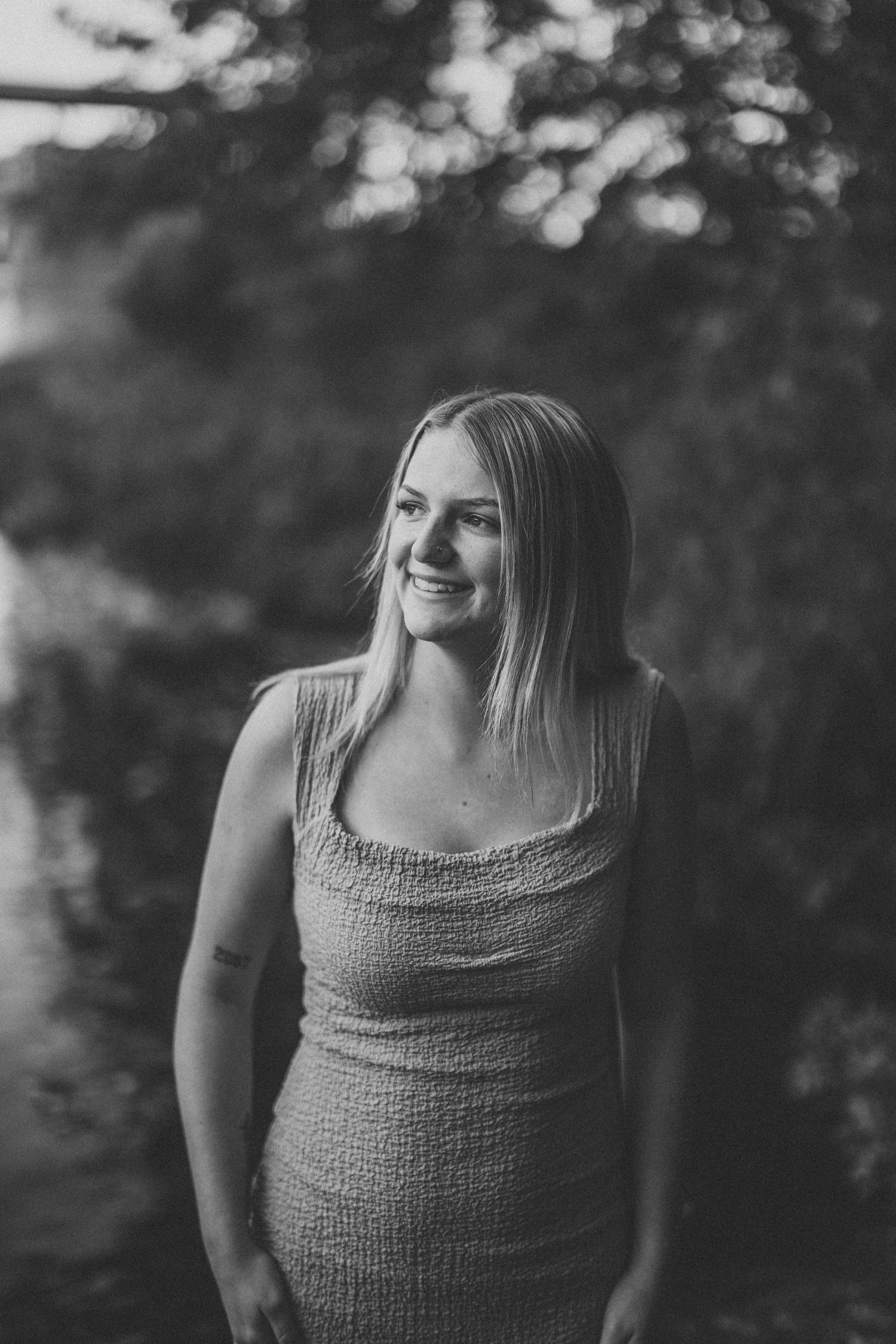 Black and white portrait series of a person in a sleeveless top against a blurred outdoor background.