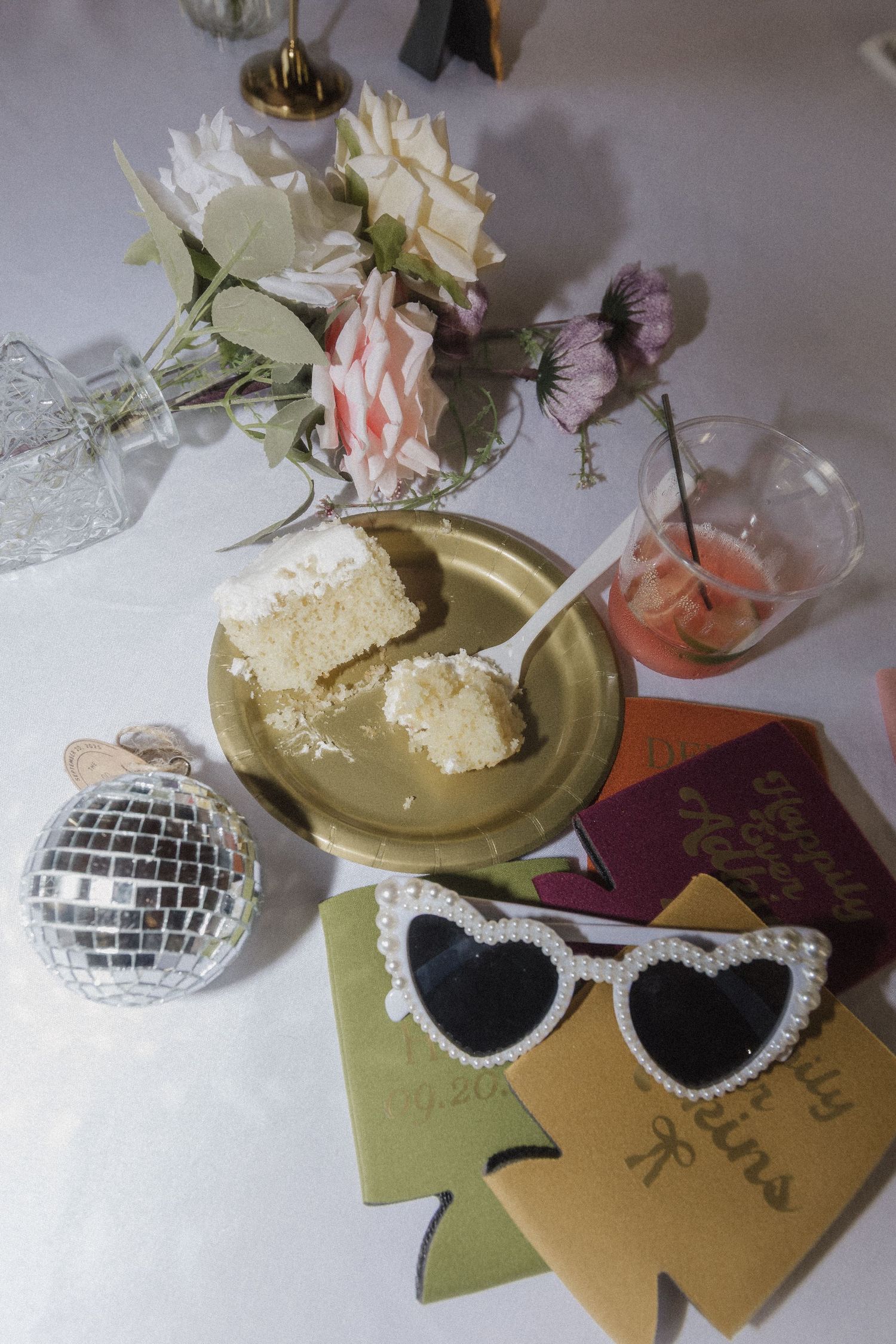 Retro white sunglasses with disco balls and floral decorations arranged on gold and green paper.